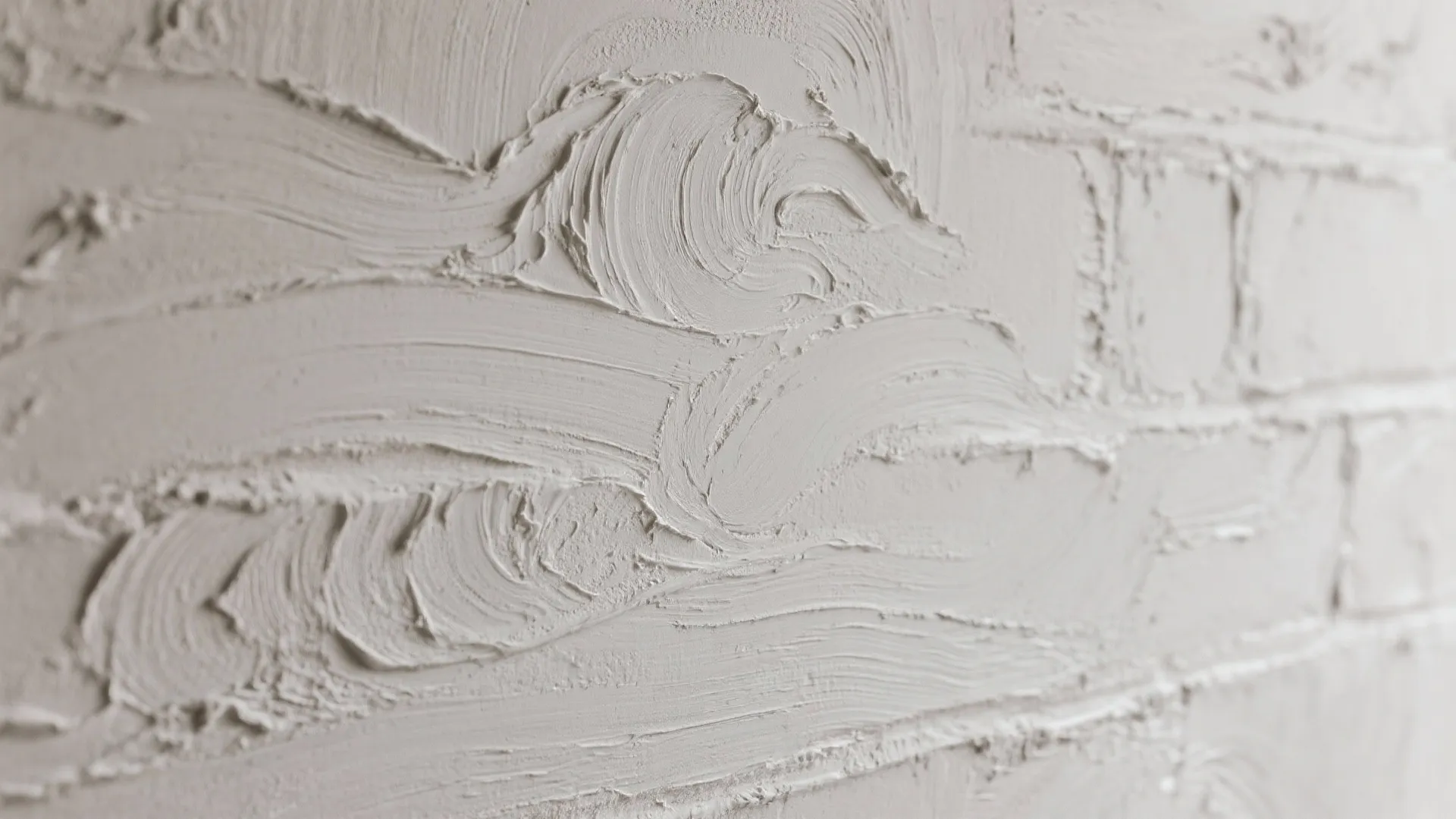 Close up view of a textured white plaster wall with thick brush strokes and patterns