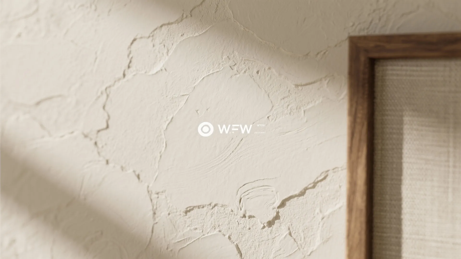 Close up view of a textured cream wall surface with natural shadows and wooden frame