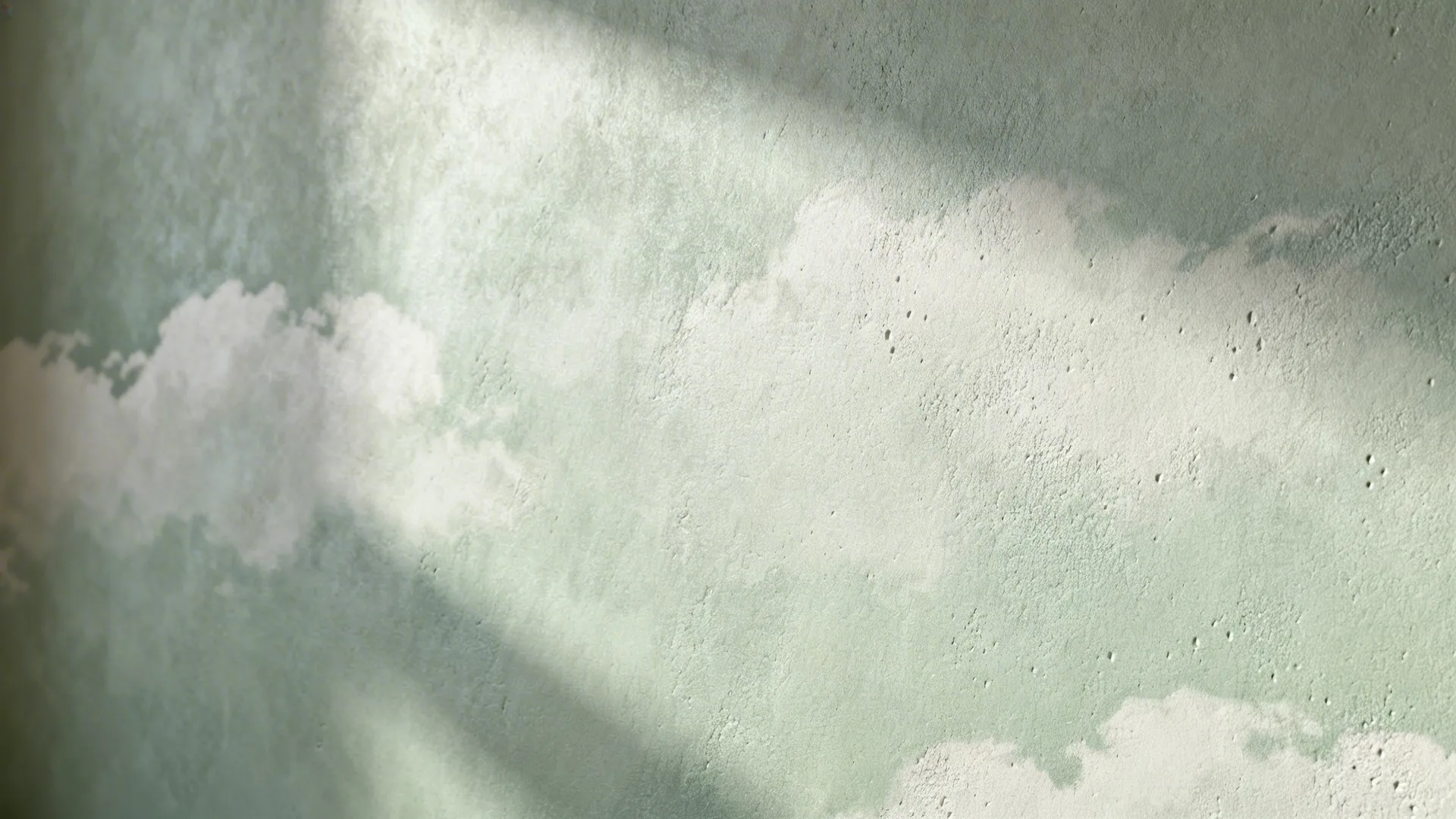 Macro of pale grey-green lime-wash wall showing matte, cloud-like texture in soft light.
