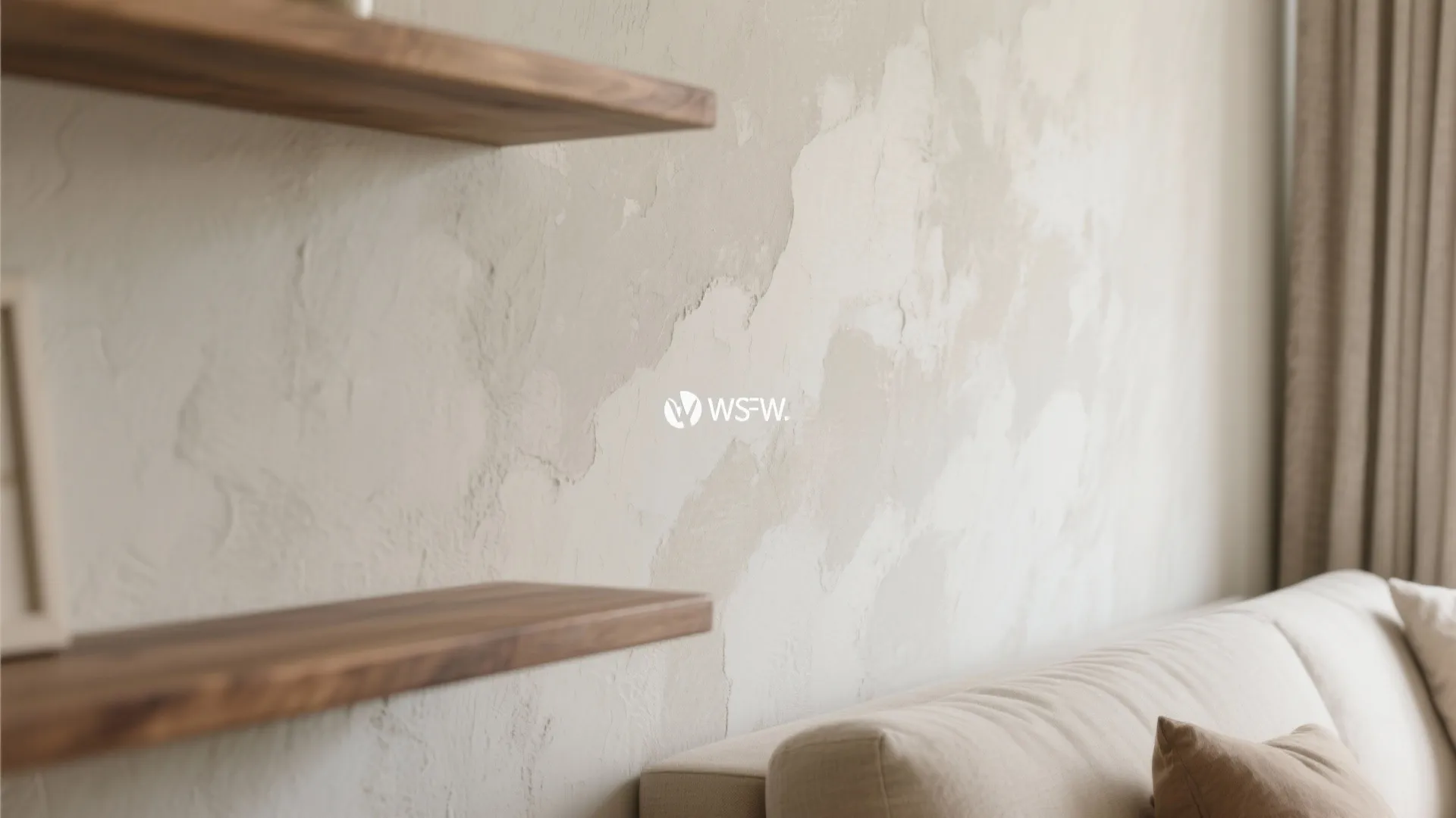 Textured beige limewash wall with two floating wooden shelves above a soft modern cream sofa