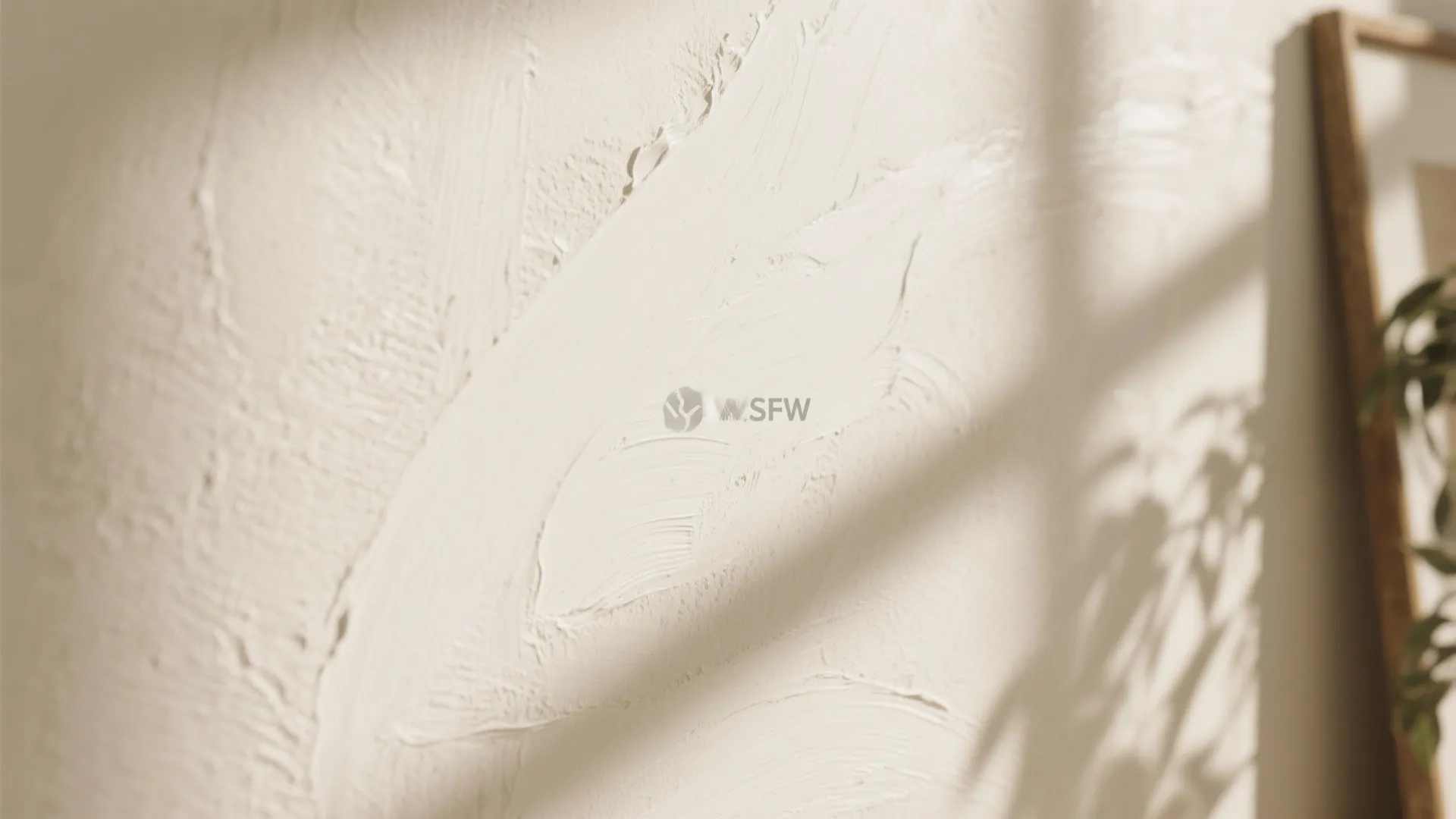 Close up view of cream textured wall paint with soft shadows from a nearby window plant