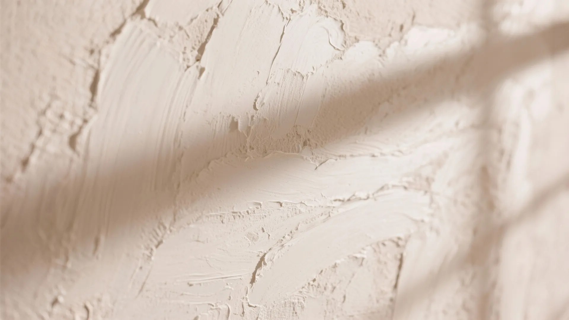 Close up view of white textured plaster wall surface with soft shadows from nearby window