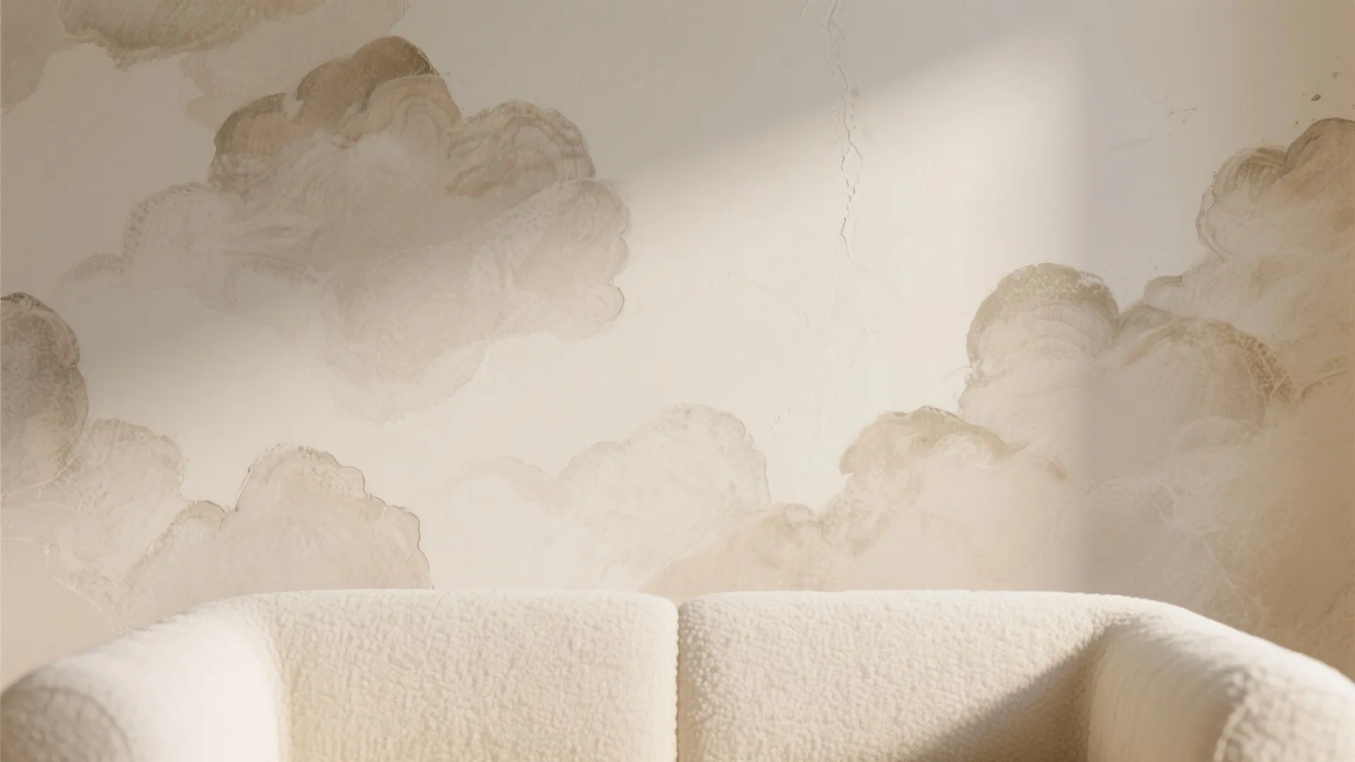 Close up view of a white sofa against a wall with textured beige cloud paint patterns