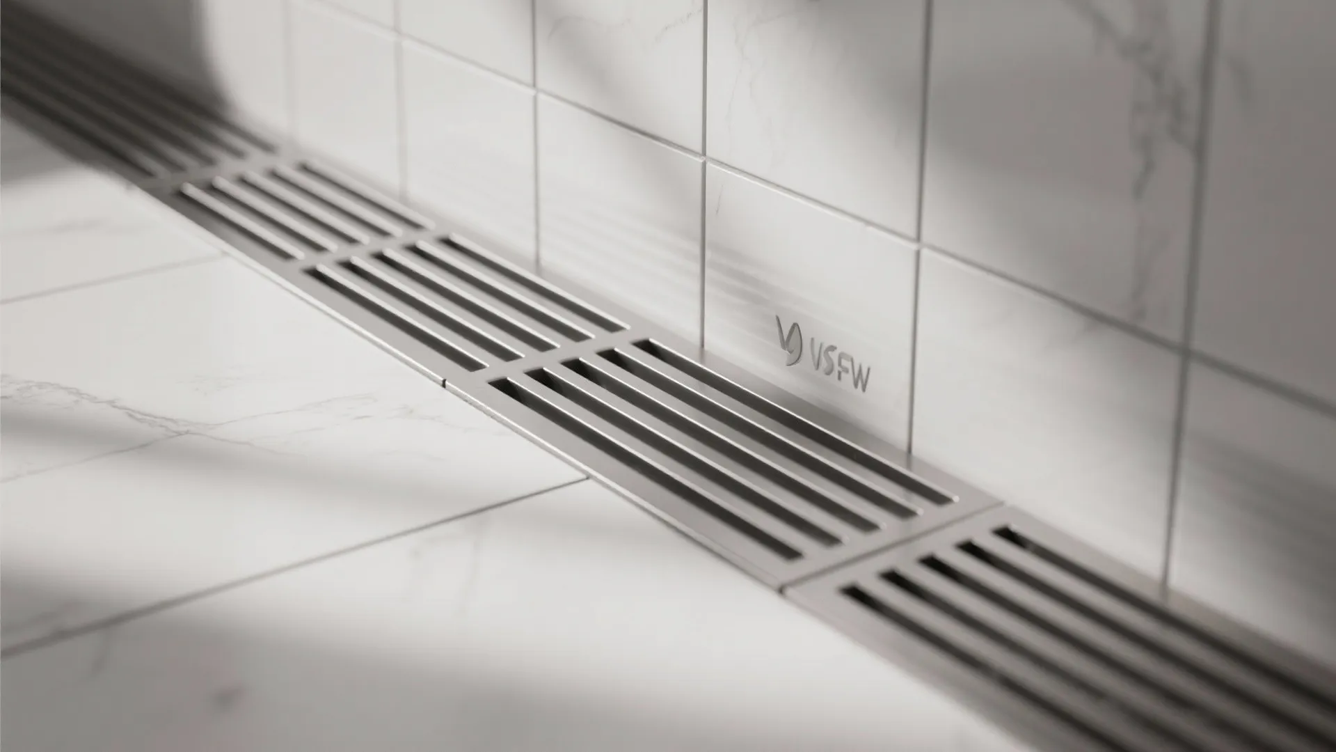 Macro of wall linear drain with brushed stainless grate and aligned large tiles.
