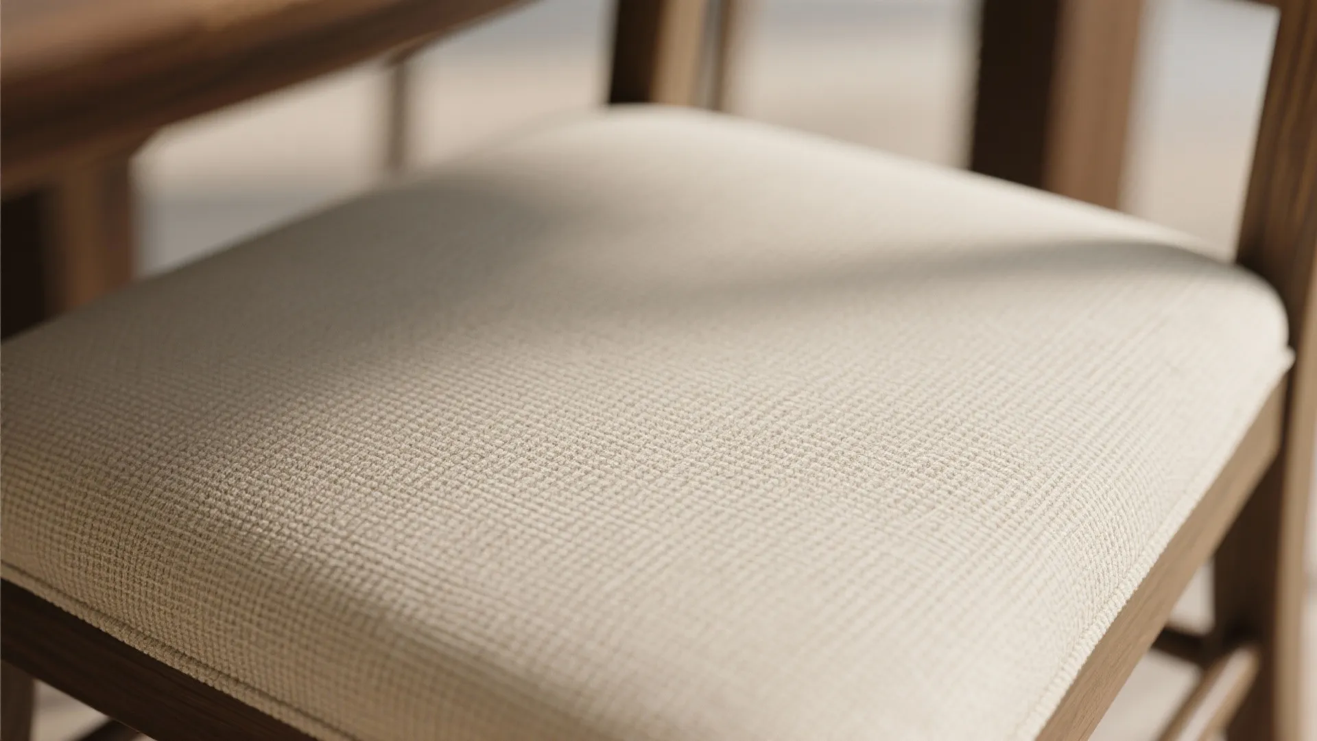 Close up of a beige textured fabric chair seat with a light brown wooden frame