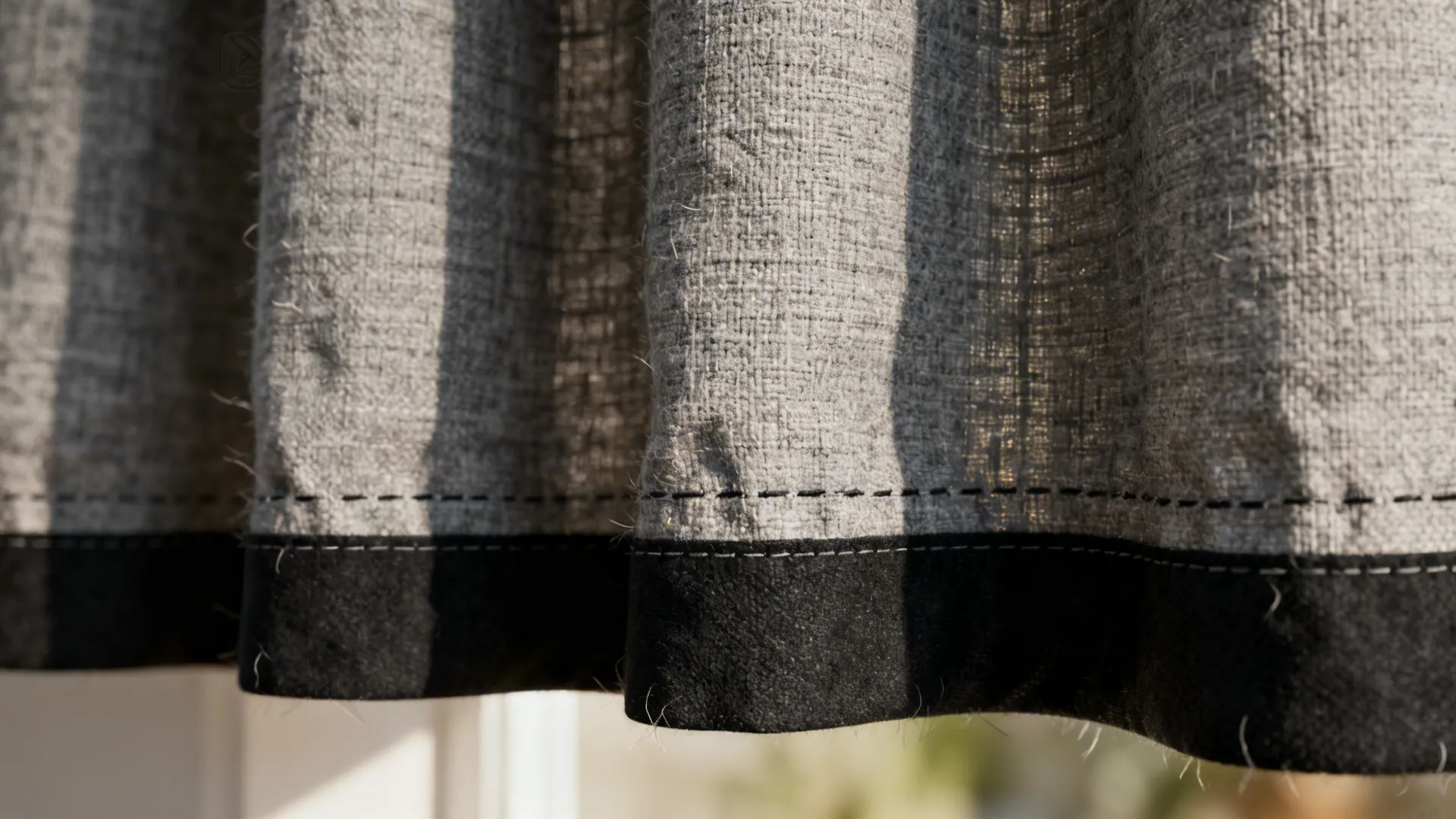 Close-up of textured grey linen curtain edged with matte black trim showing fabric weave
