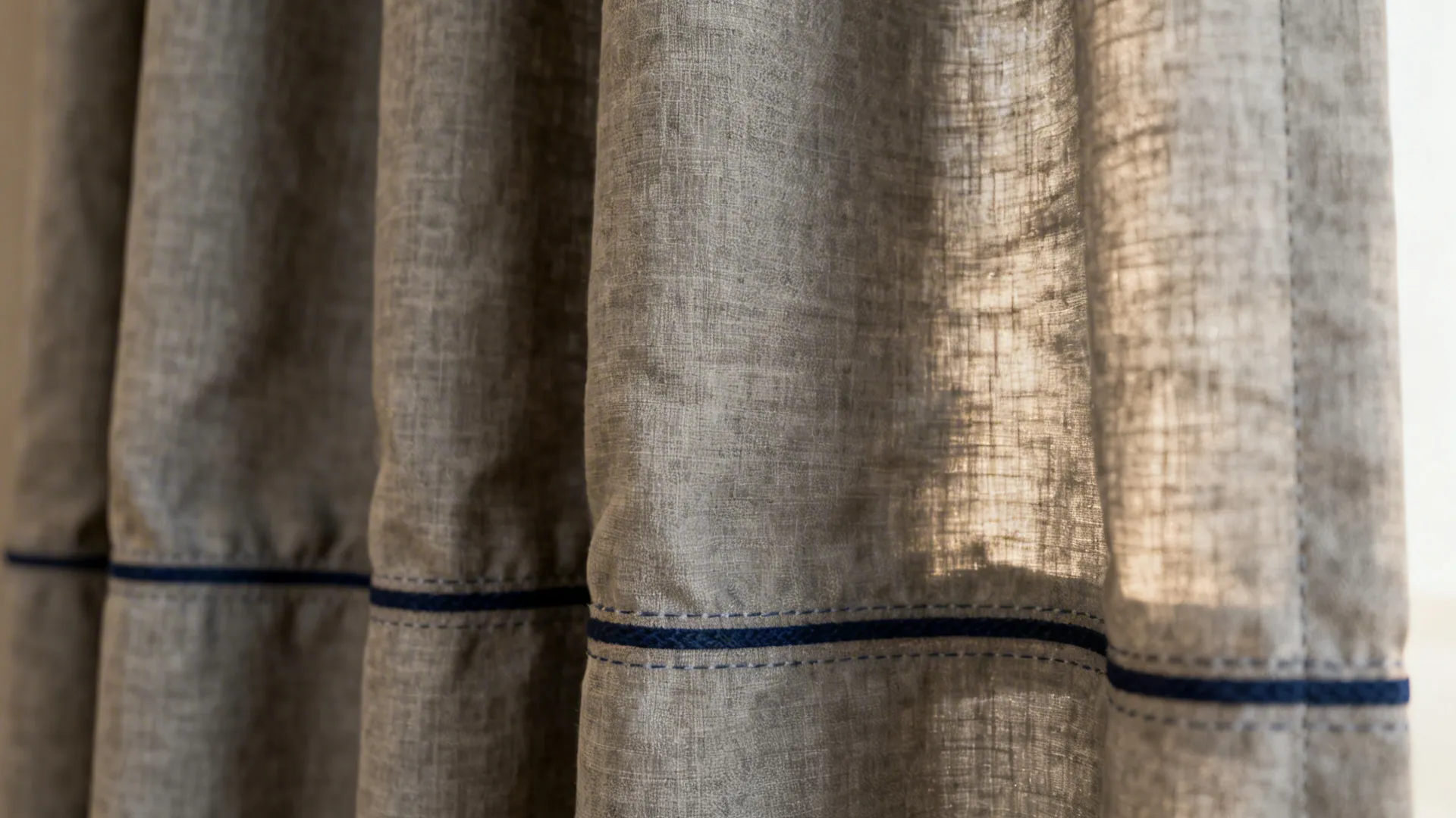 Slate-grey linen curtain with navy trim showing textured weave and gentle wrinkles