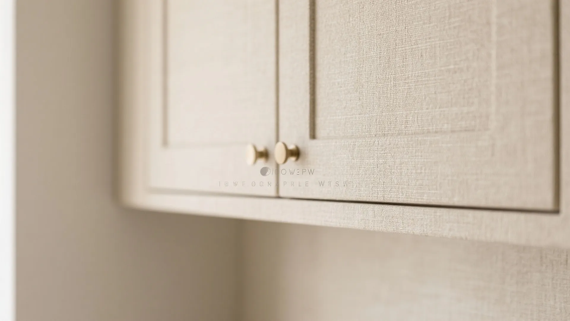 Close up of beige fabric texture kitchen cabinet doors with small round gold metal door handles