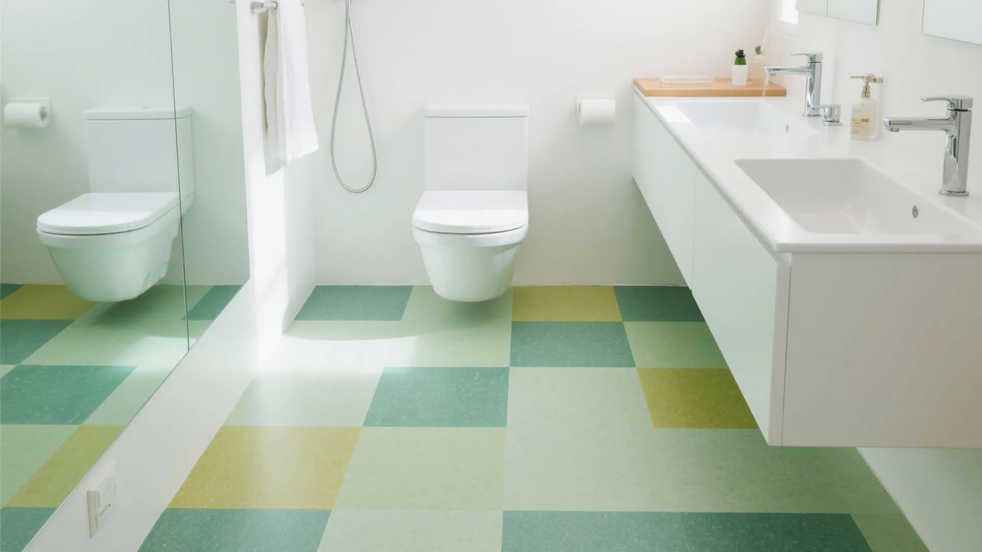 Bright bathroom with green checkered floor tiles plus white wall toilet and a double sink