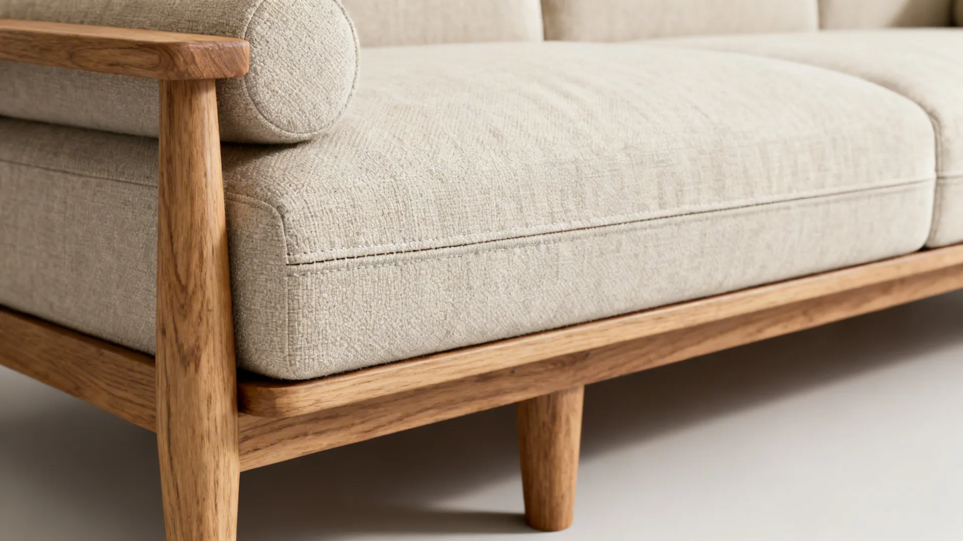Close-up of a slim-lined loveseat with exposed legs and textured neutral upholstery.