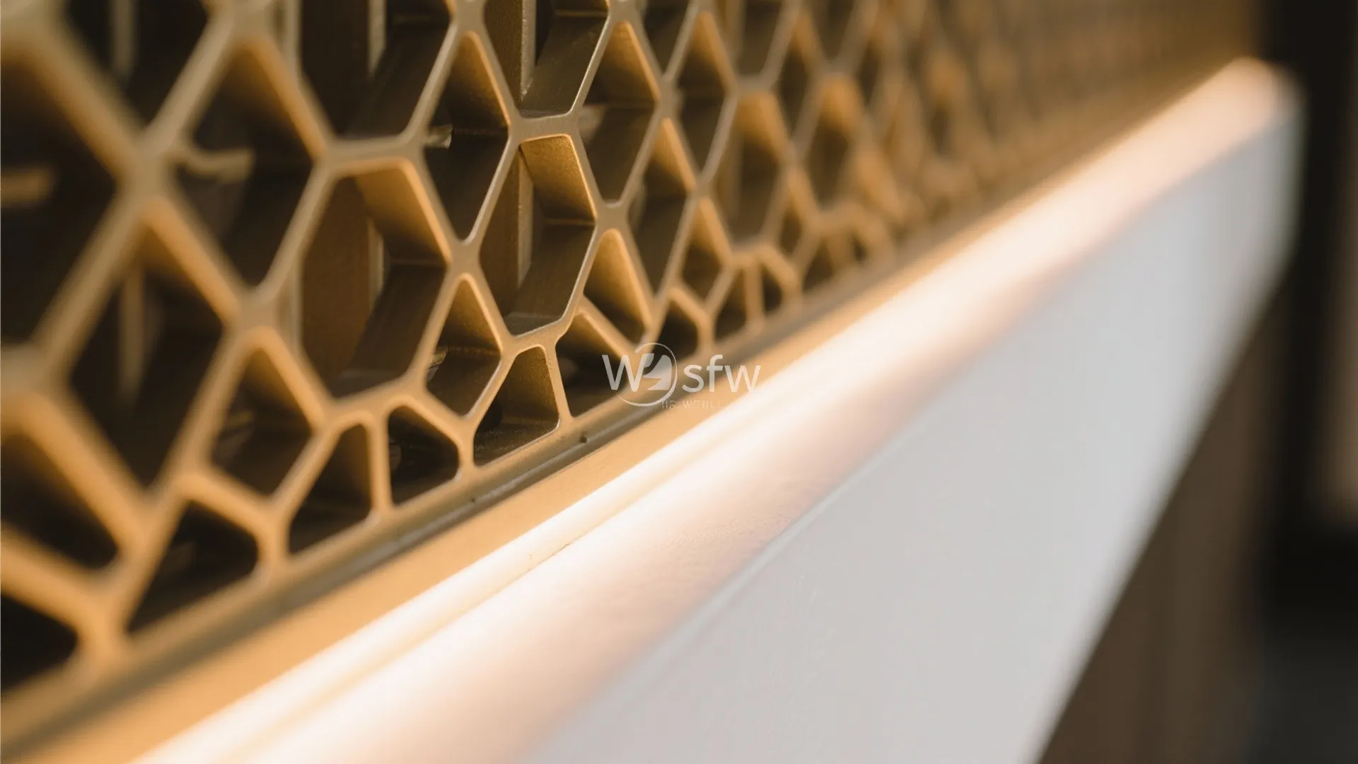 Macro of softly diffused warm LED highlighting a jali edge with brushed brass and matte white detail.
