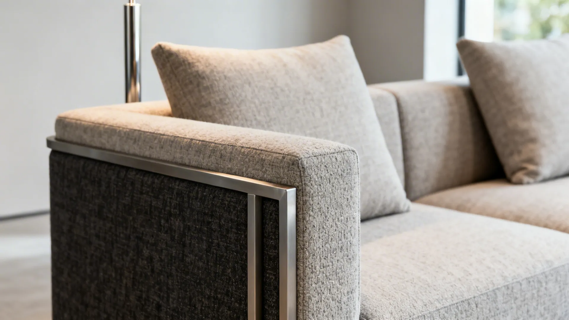 Detail of a low-back L-shaped sofa with slim arms and floor lamp behind it.