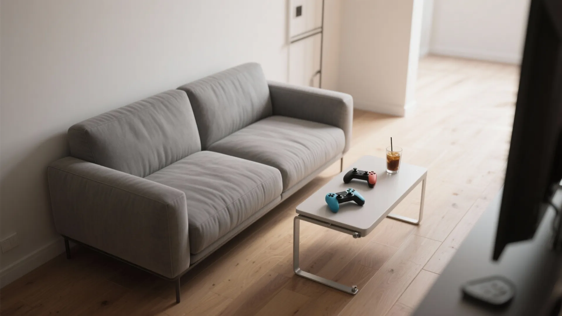 Modern grey sofa in living room with a coffee table holding controllers and iced drink
