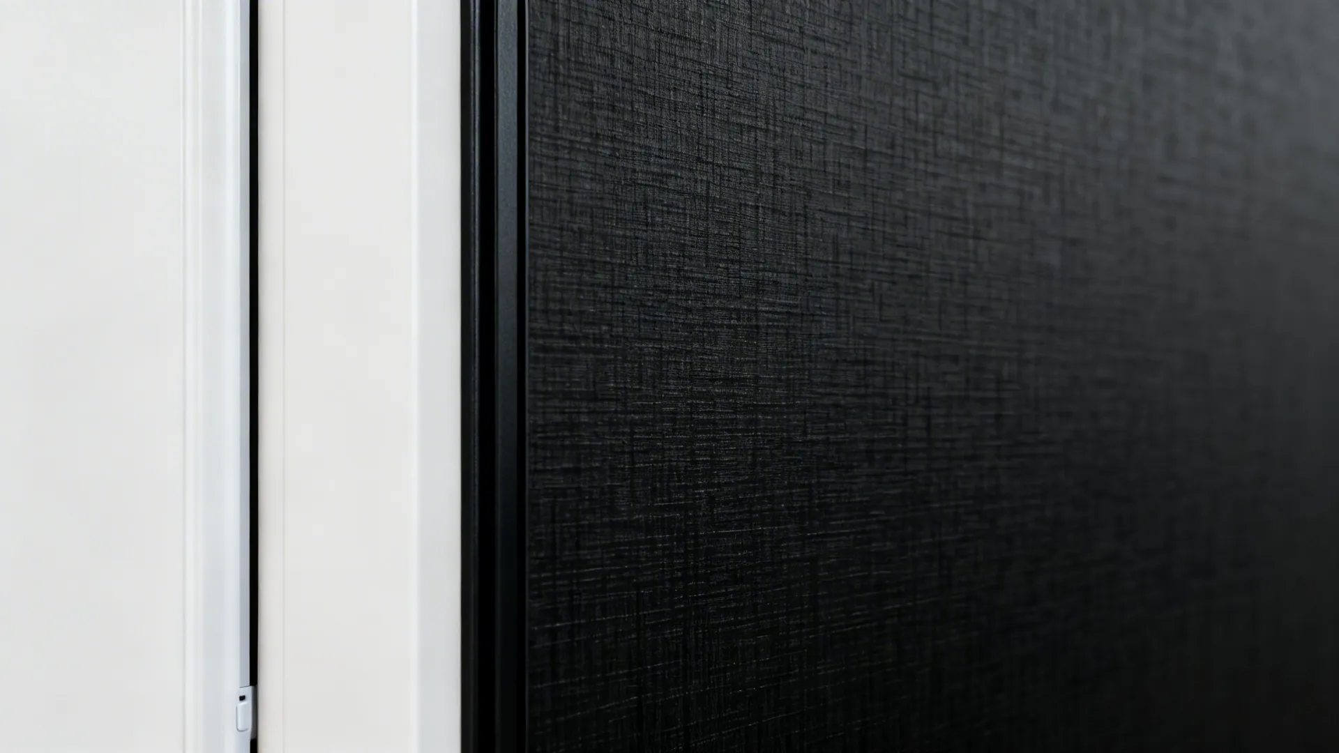 Macro of textured black laminate beside white door with slim black edge.