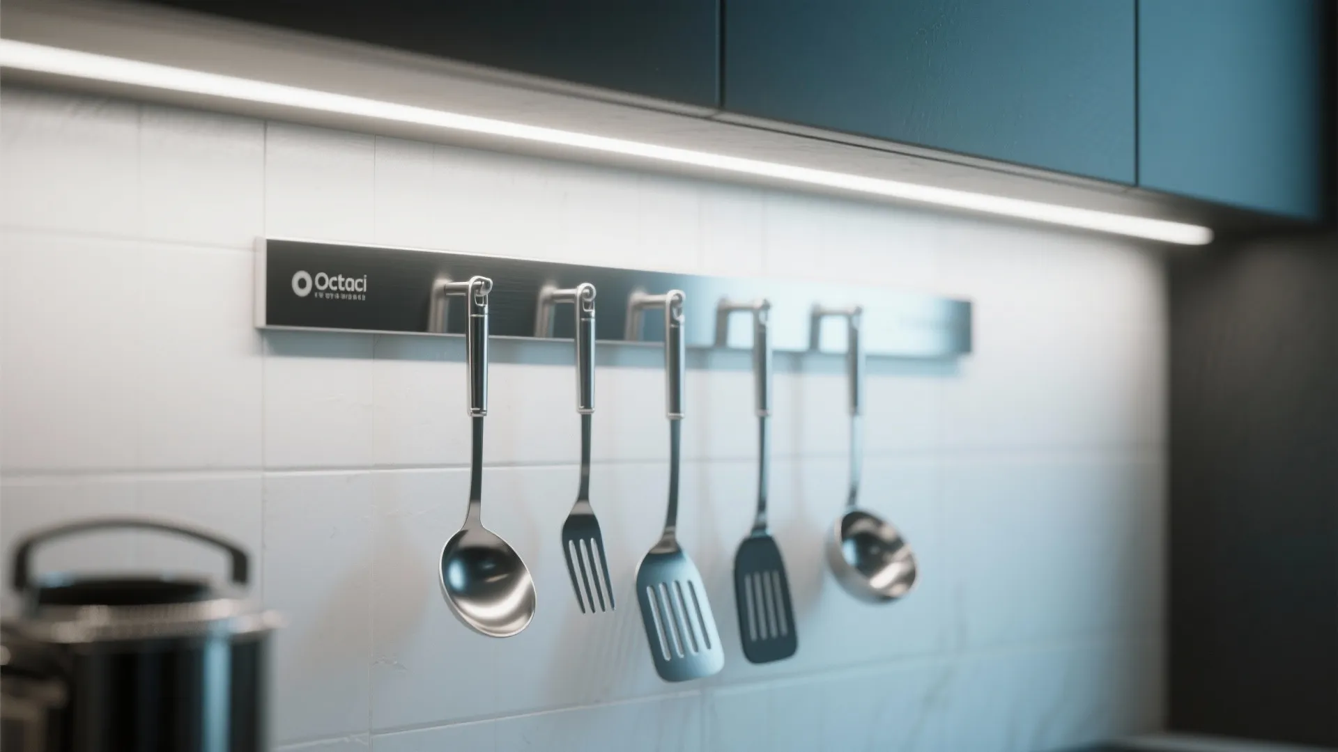 Kitchen utensils hanging on metal bar against white tiled wall with a bright strip light