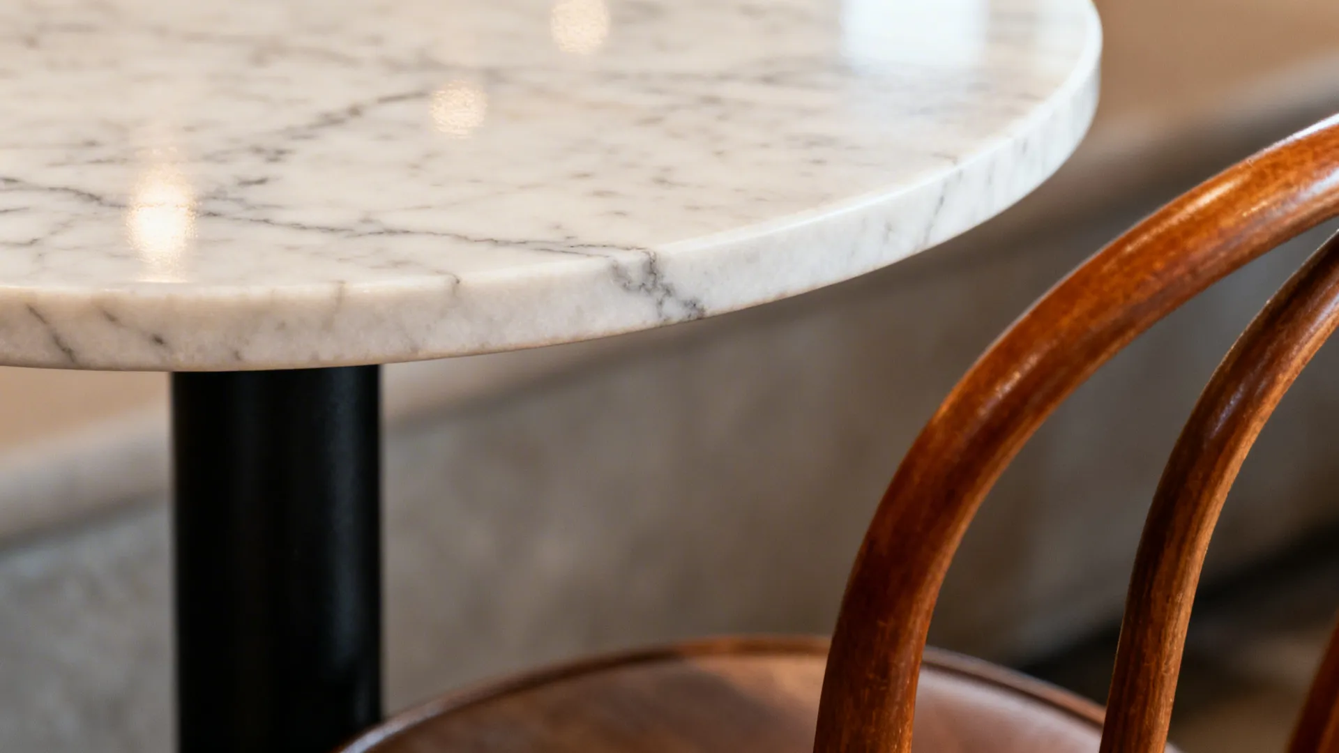 Macro of marble café table edge and curved bentwood chair detail.