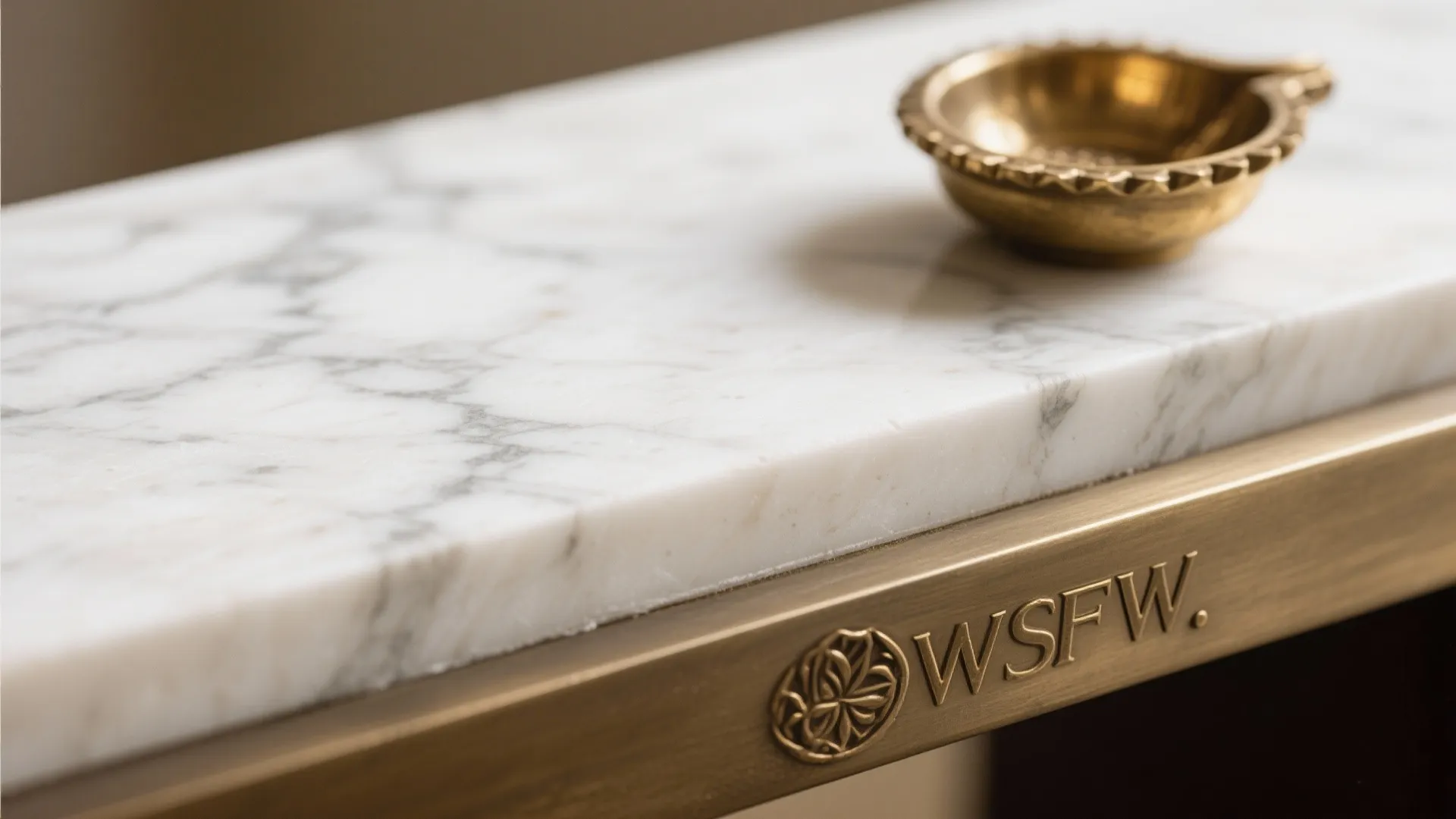 Close up of a white marble table top with a gold bowl and brass edge