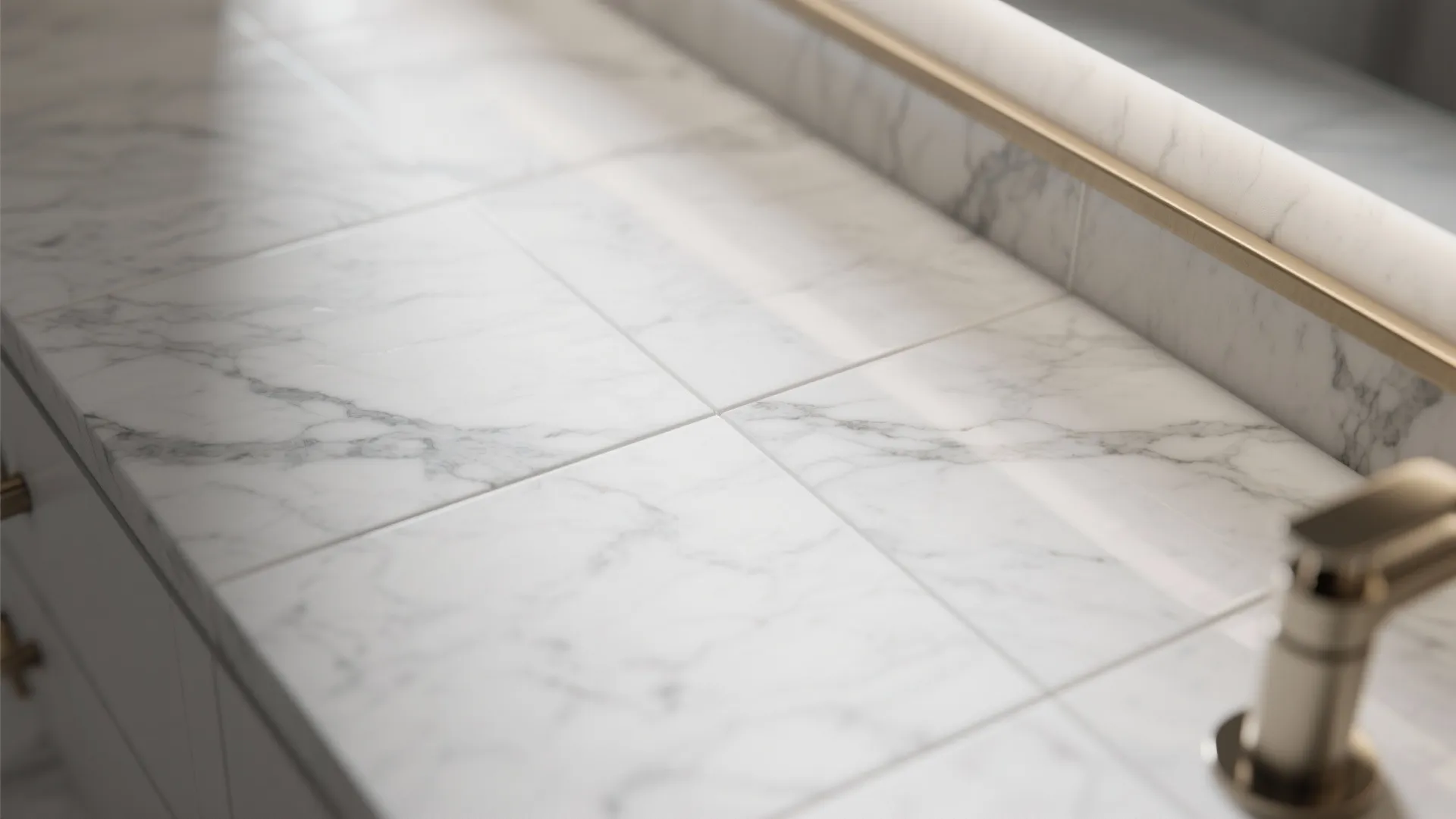 Close up view of white marble tiles on a bathroom cabinet with gold sink faucet