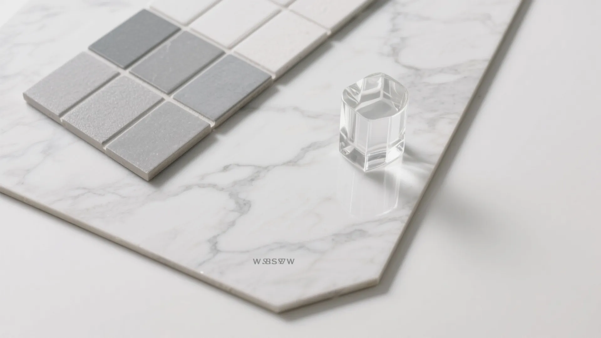 White marble slab with grey and white square tile samples and a small clear glass