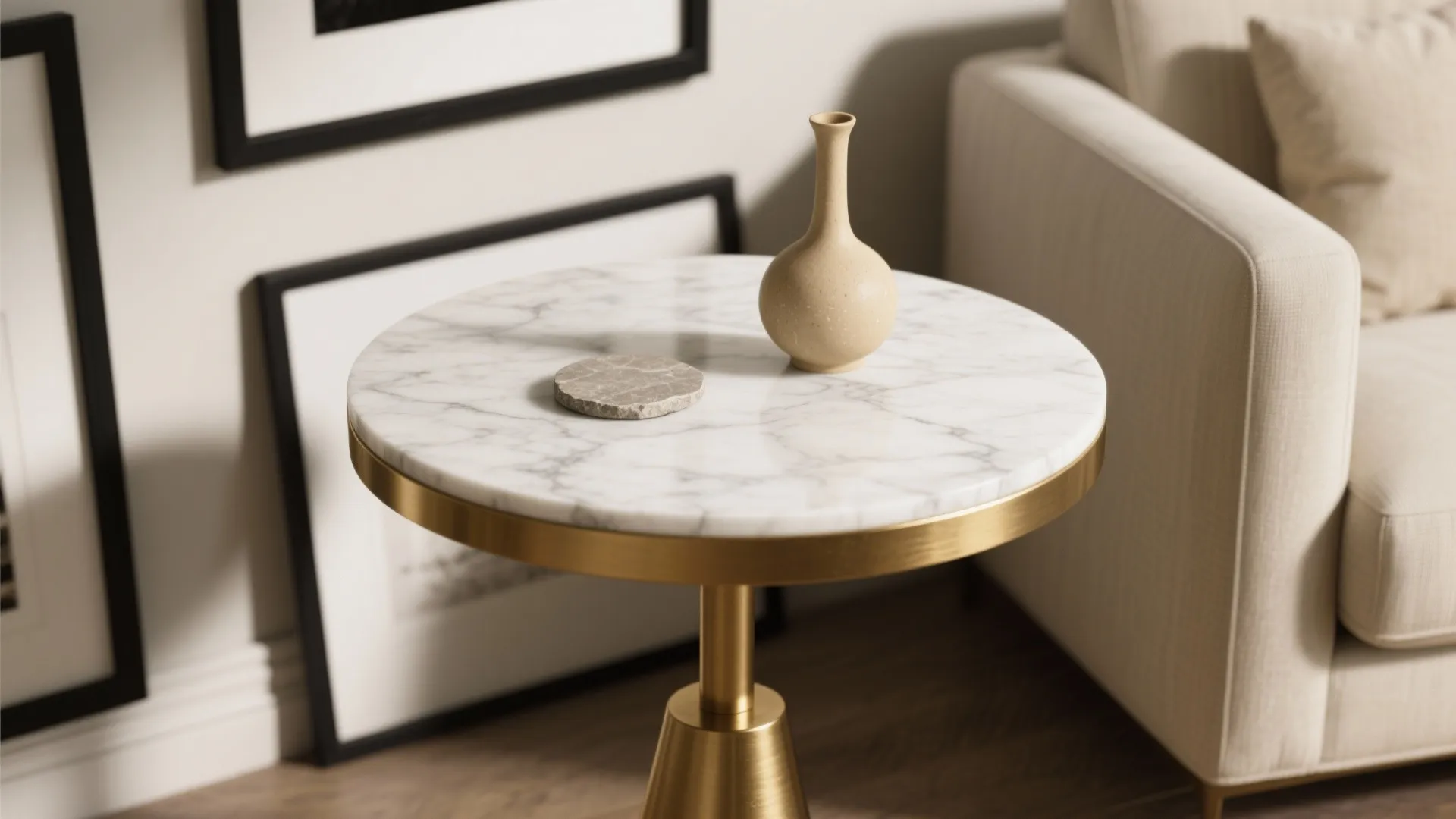 Petite marble top small gold side table with brushed gold base beside a linen sofa
