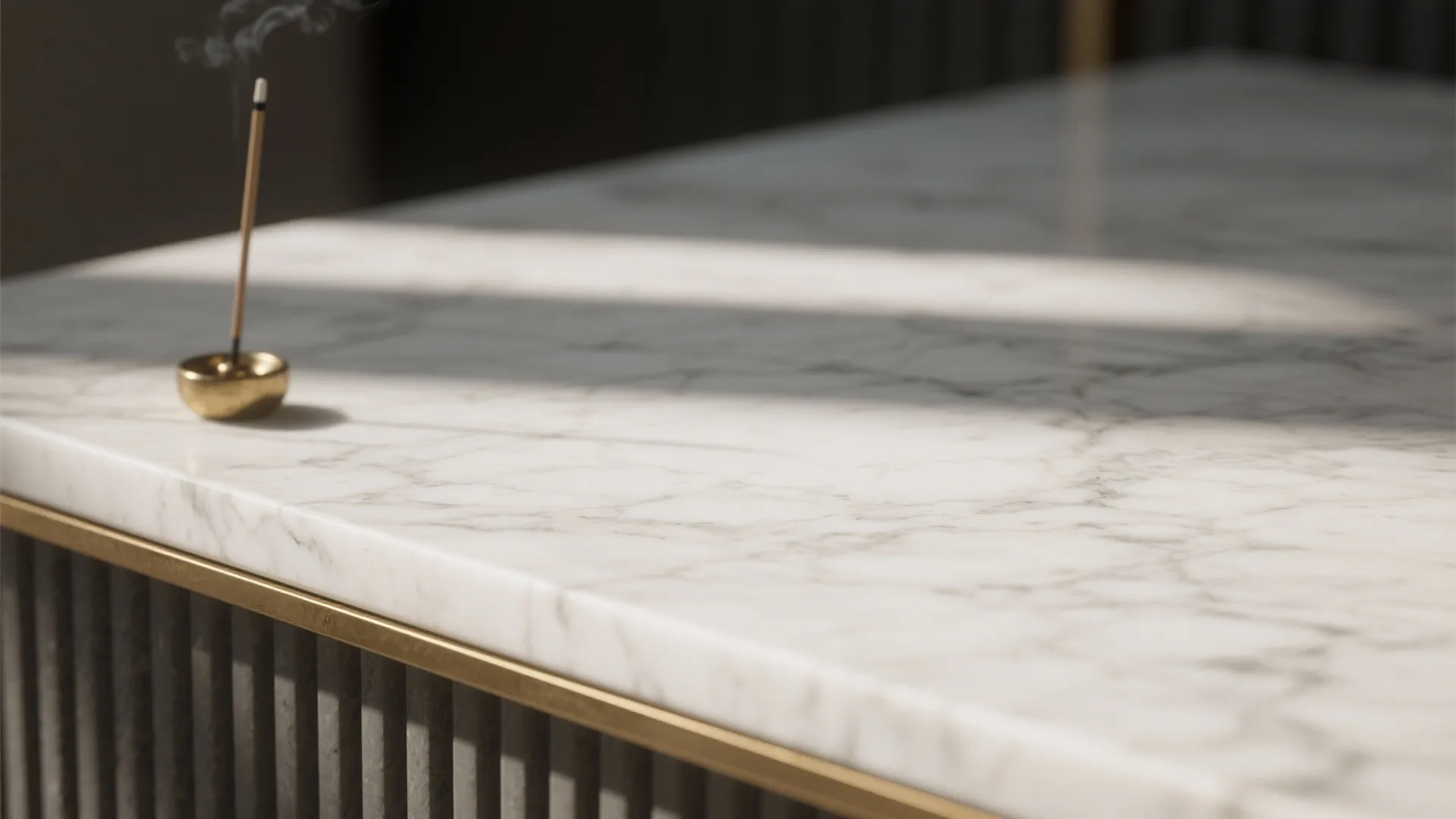 Macro view of honed white marble veining beside a brass ledge.