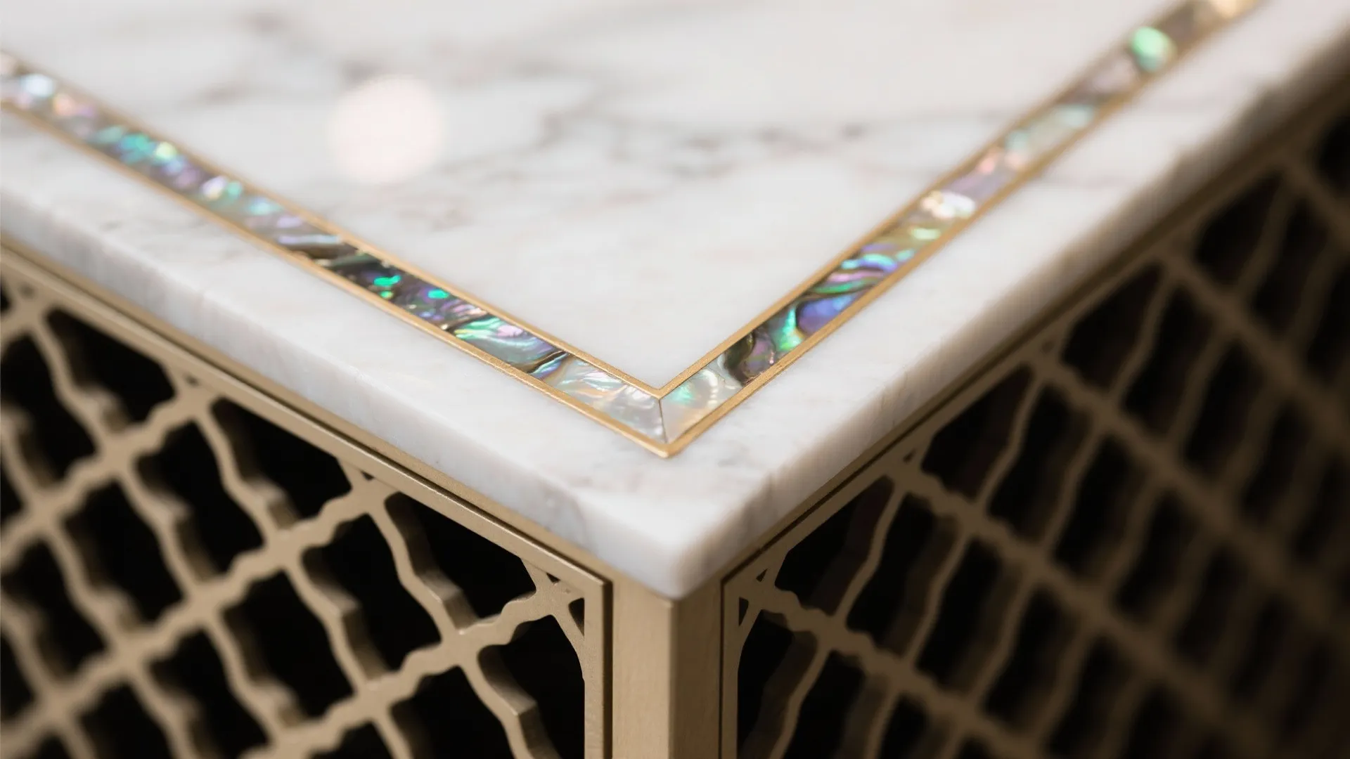 White marble table top with colorful shell border and gold metal base with geometric pattern detail