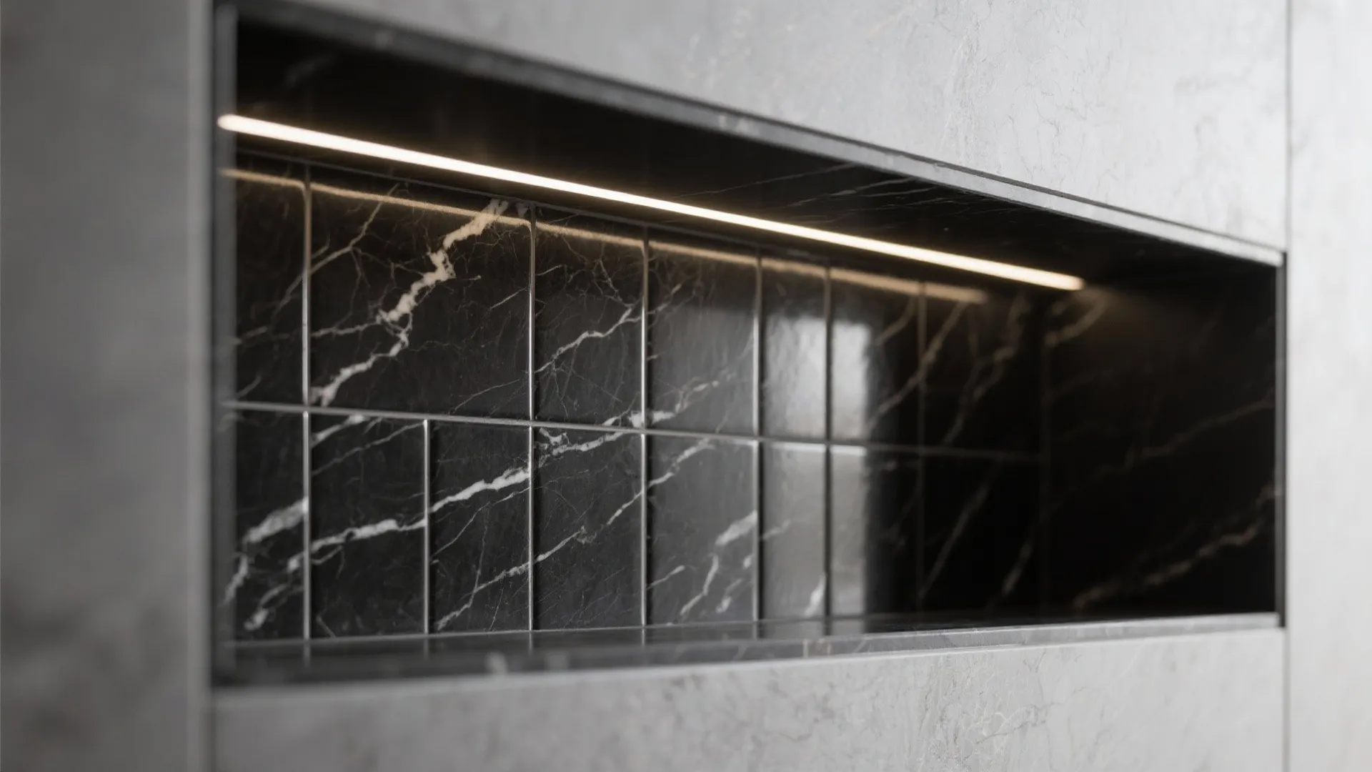 Macro detail of a black marble tiles niche with aligned veins, crisp stone edges, and soft LED accent lighting in a compact bathroom.