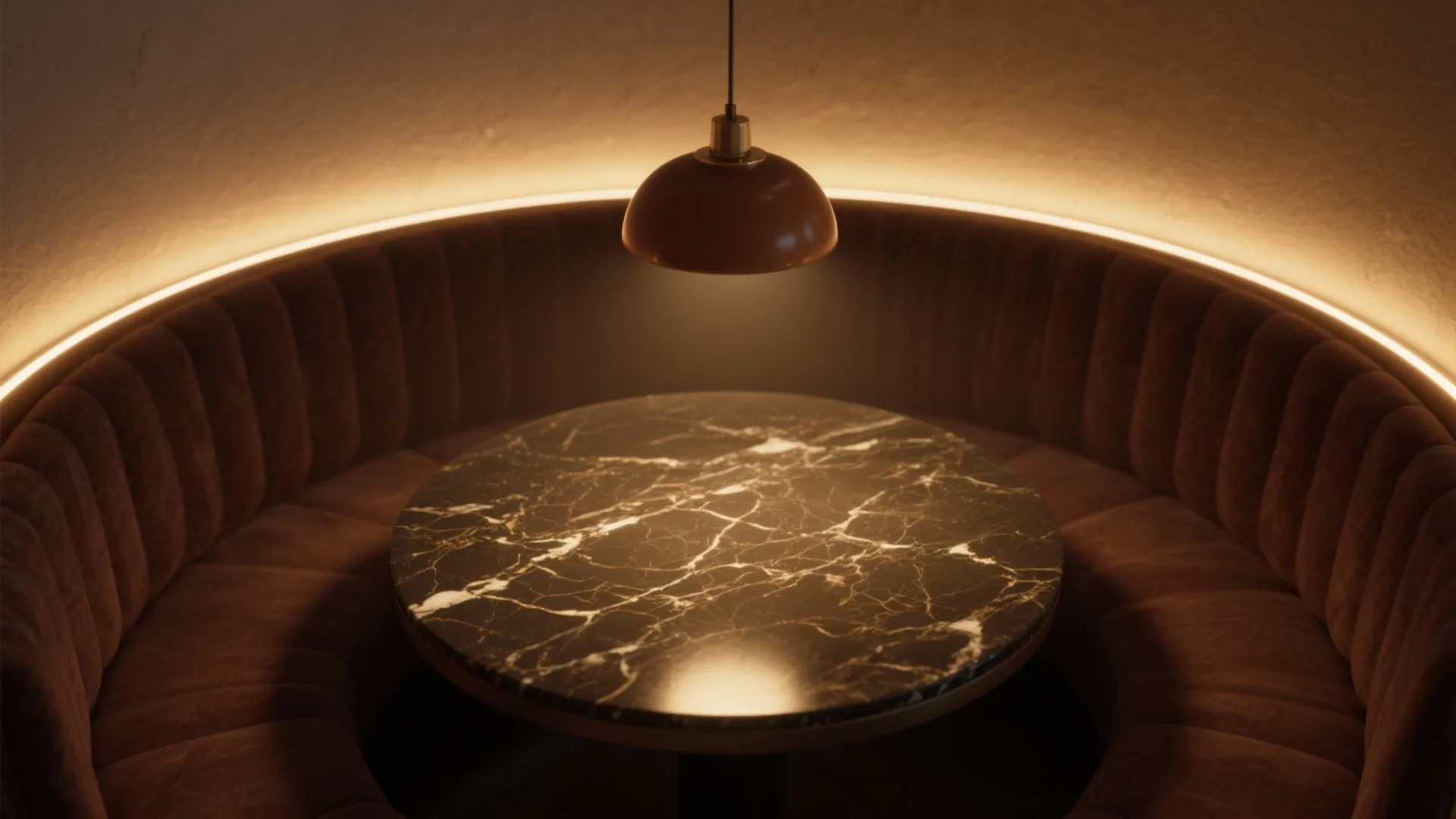 Dark brown marble table under a round ceiling light with a curved soft velvet wall seat