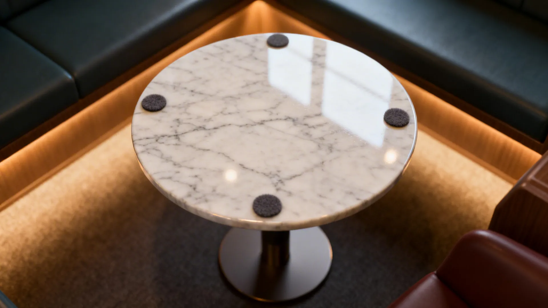 Close-up of a sealed marble round table top with visible veining and protective felt pads