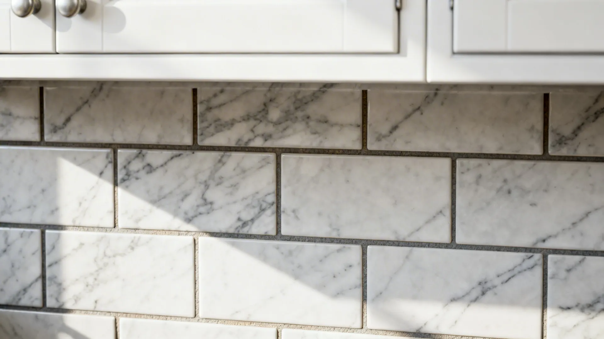 Close-up of marble-patterned subway tile with darker grout behind white cabinetry