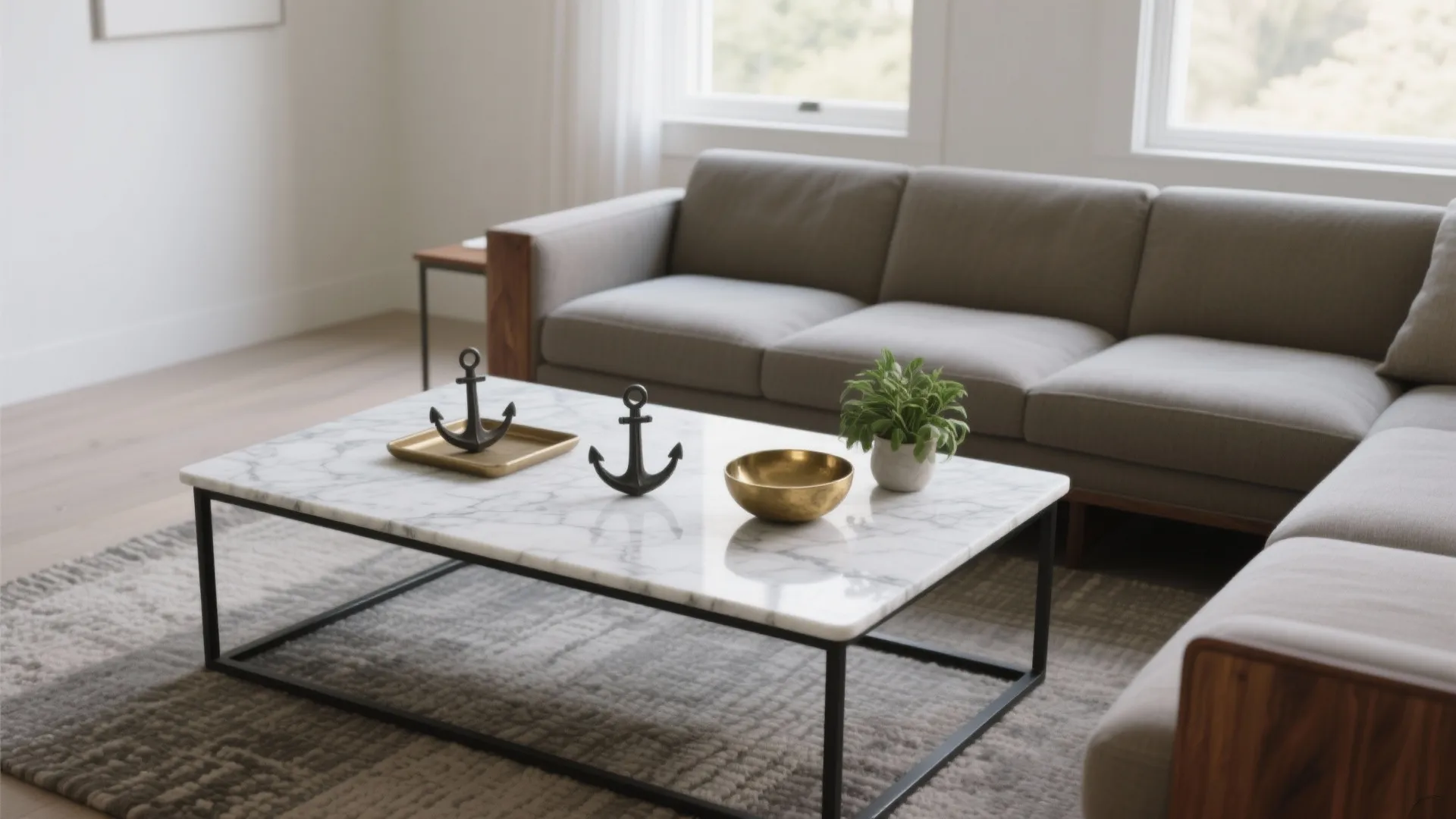 Modern living room with marble coffee table, grey sofa, small green plant, and natural light
