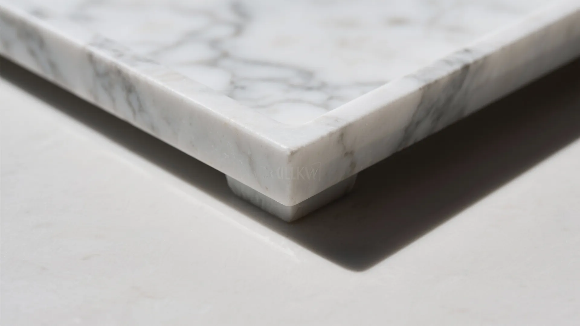 Close up view of a white marble tray corner showing natural grey stone texture and shadow