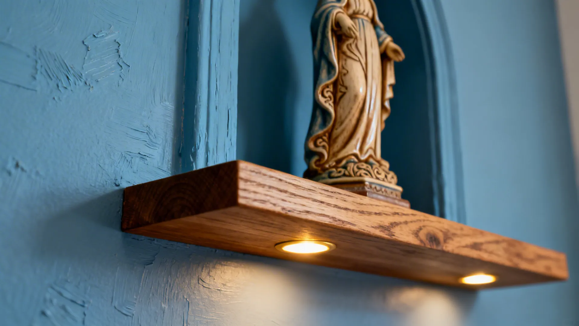 Macro of Marian blue niche paint with statue detail under warm spot lighting.