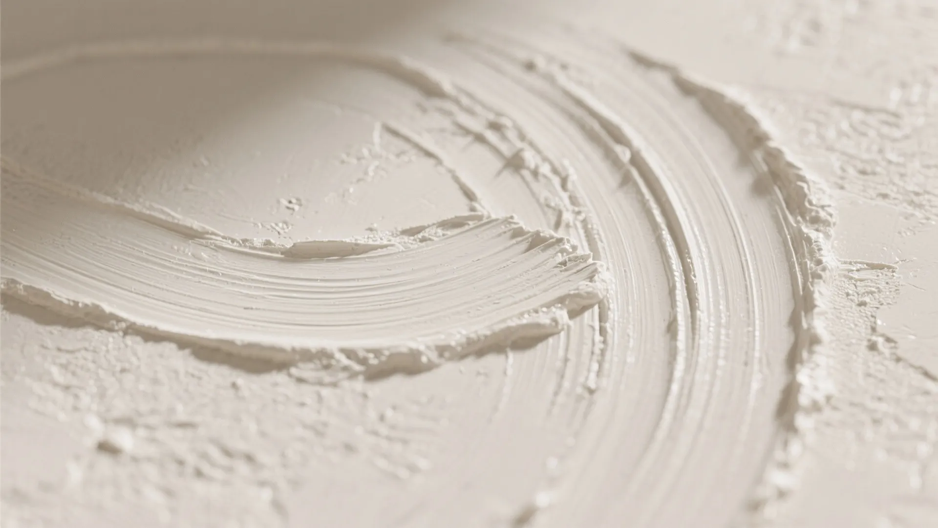 Macro close up of white textured wall plaster with circular brush strokes and soft lighting