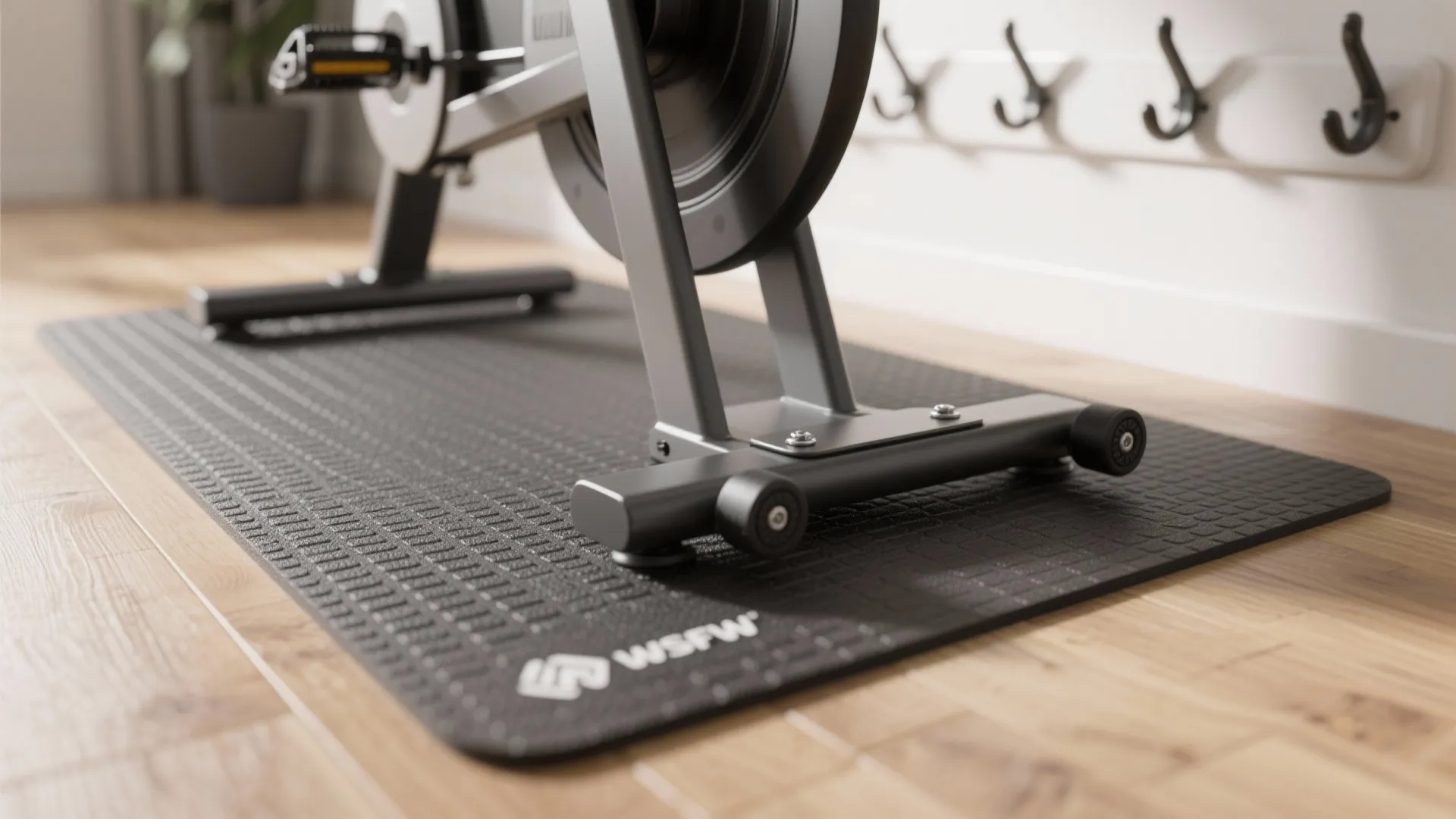 Close up of a black workout mat under an exercise machine on a wooden floor