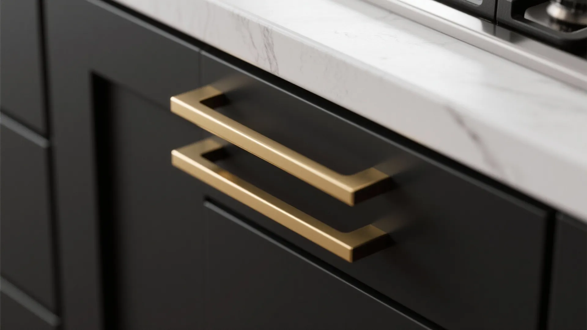 Two long gold handles on a black kitchen drawer under a white marble stone kitchen counter
