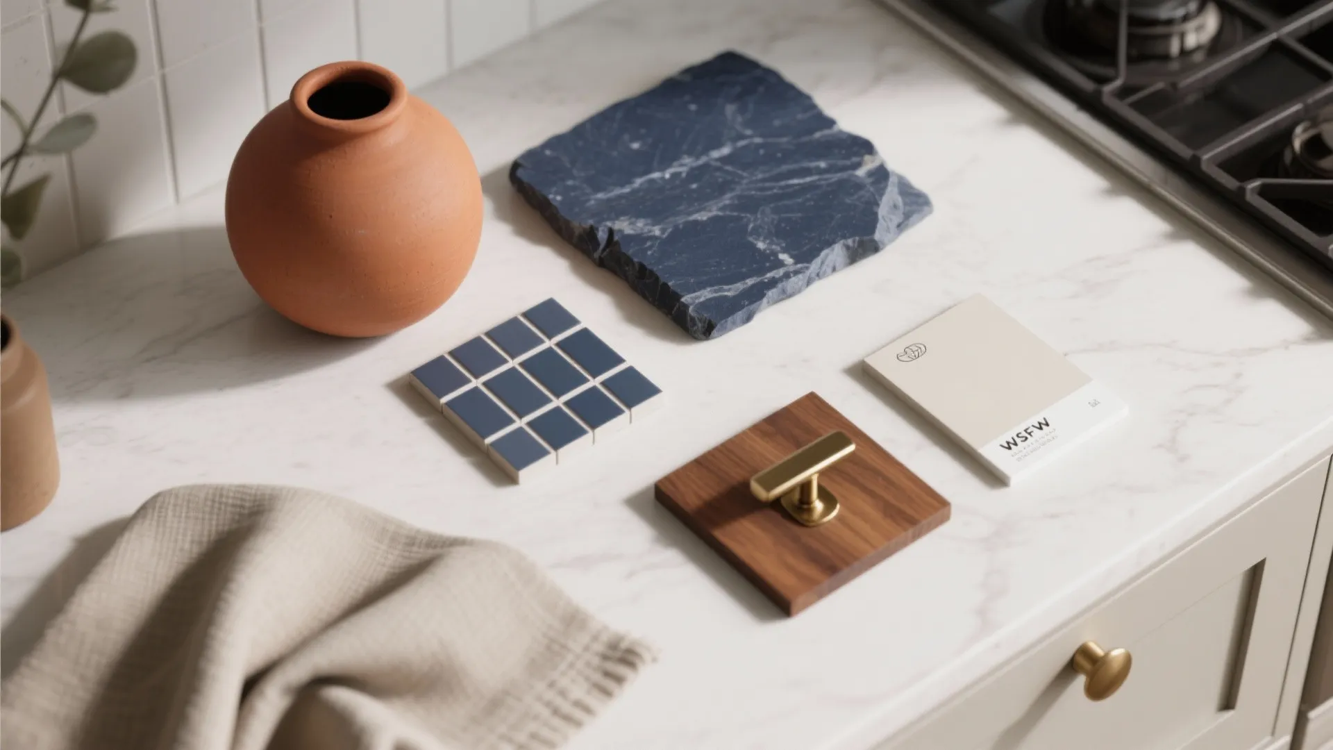 Flatlay of navy stone, terracotta vase, wood and brass samples for kitchen palette