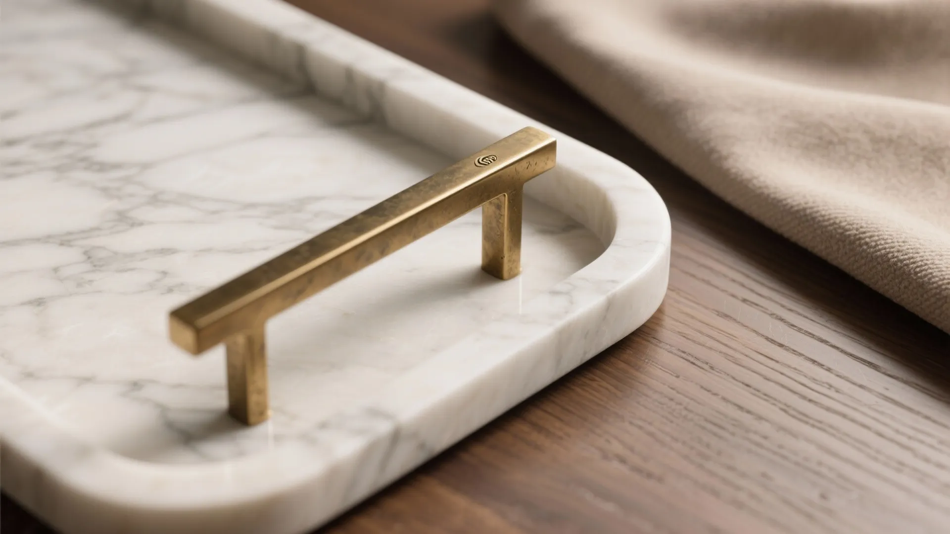 Close-up of a white marble tray with gold metal handle on a dark wood table