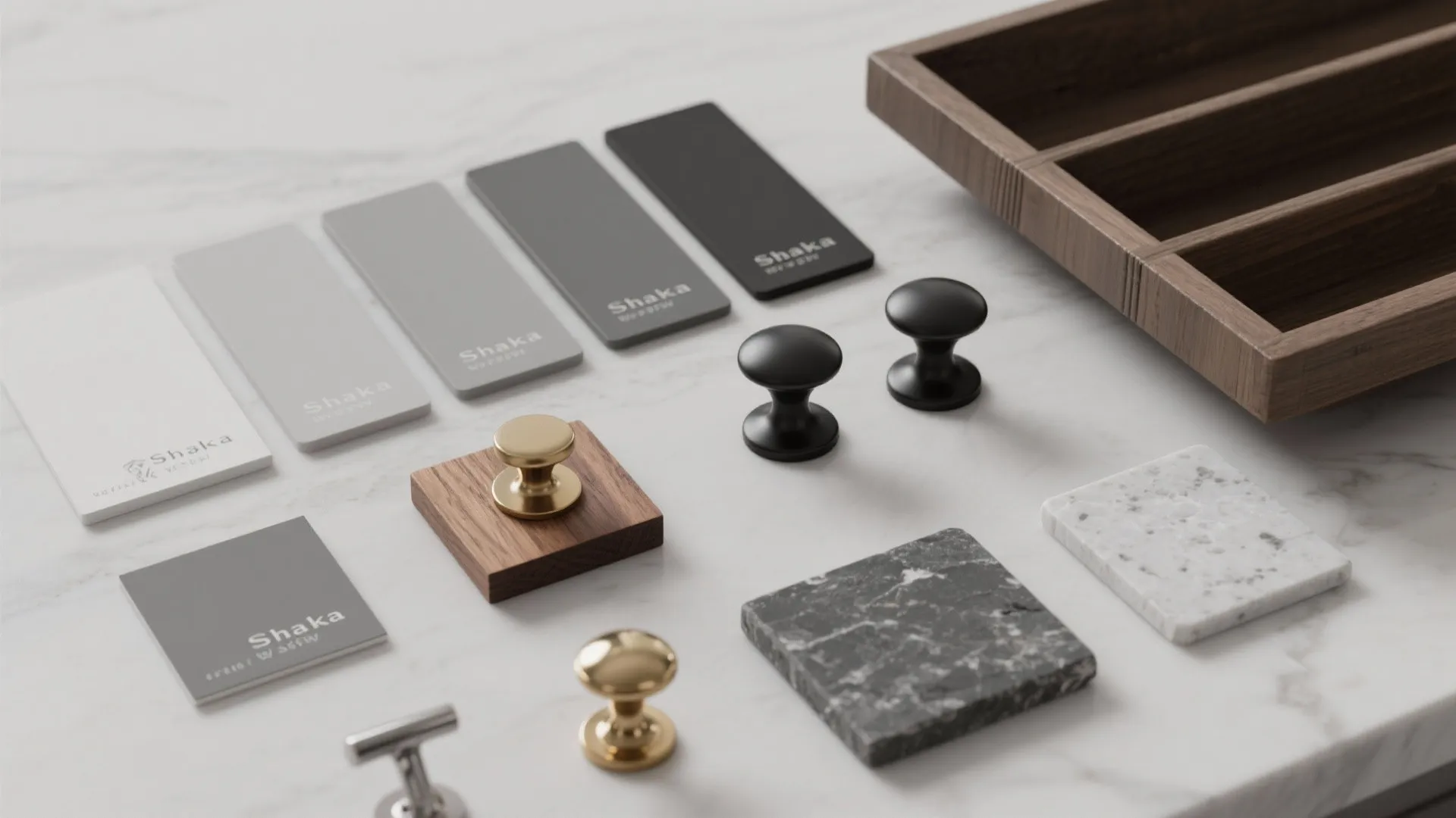 Flatlay of gray paint swatches, hardware samples and wood sample for Shaker kitchen decisions