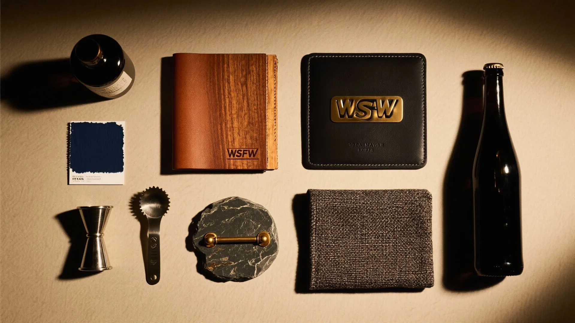 Wood folder, leather coaster, metal bar tools, fabric swatch, color card, and glass bottles arrangement