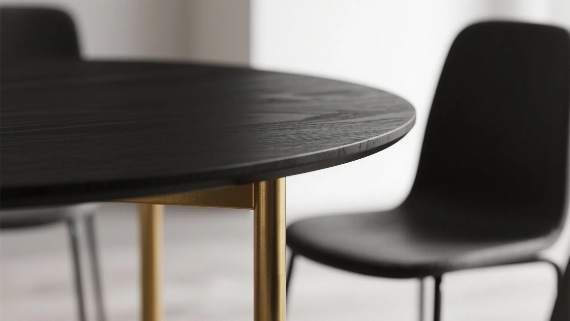 Close up of a black wooden round dining table with gold legs and black chairs