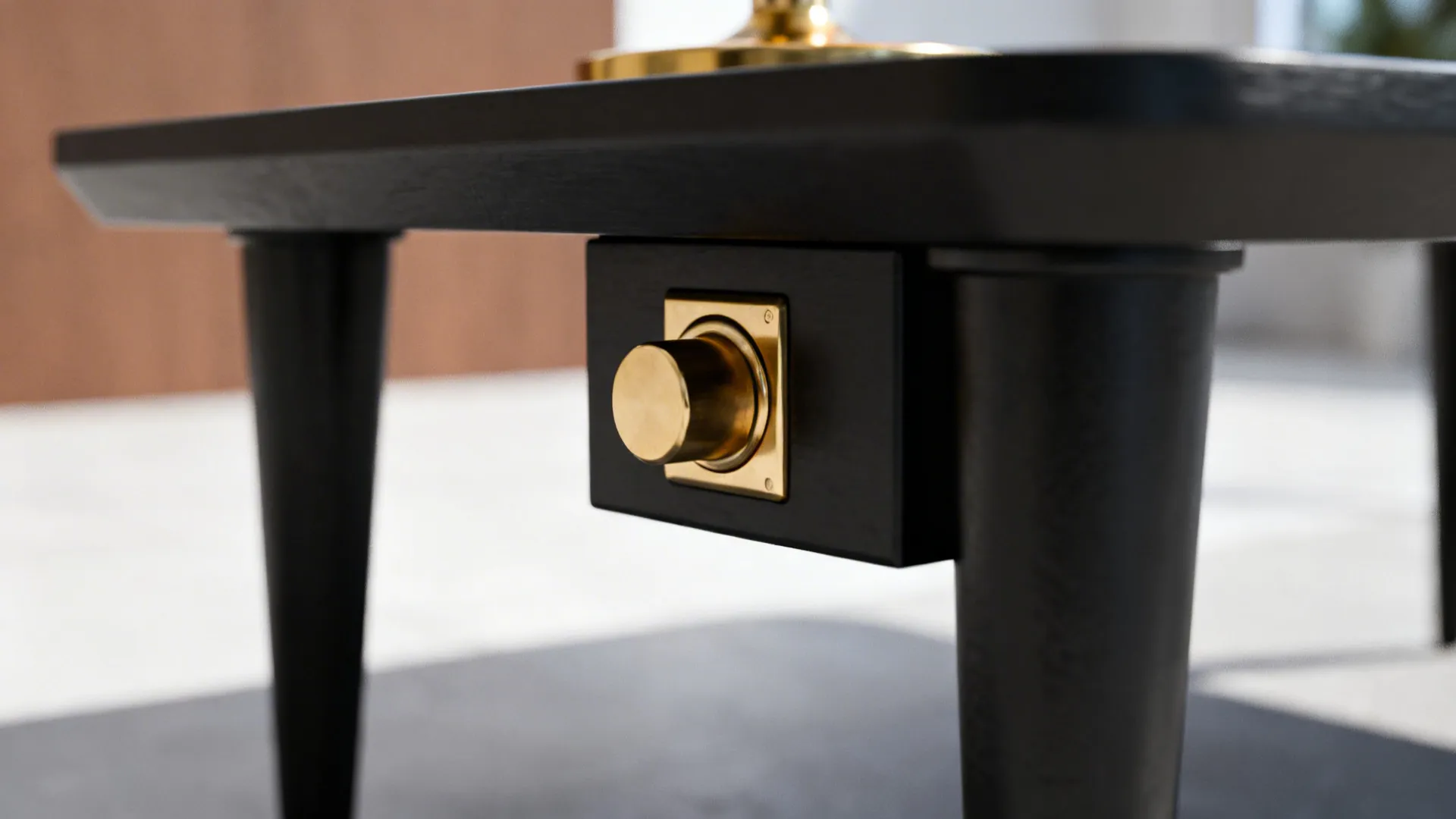 Close-up of matte black table leg and brass lamp switch on brown white grey background