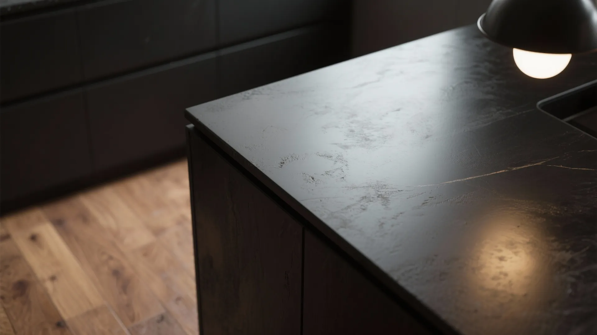 Close up view of a matte black kitchen island with textured stone surface and light