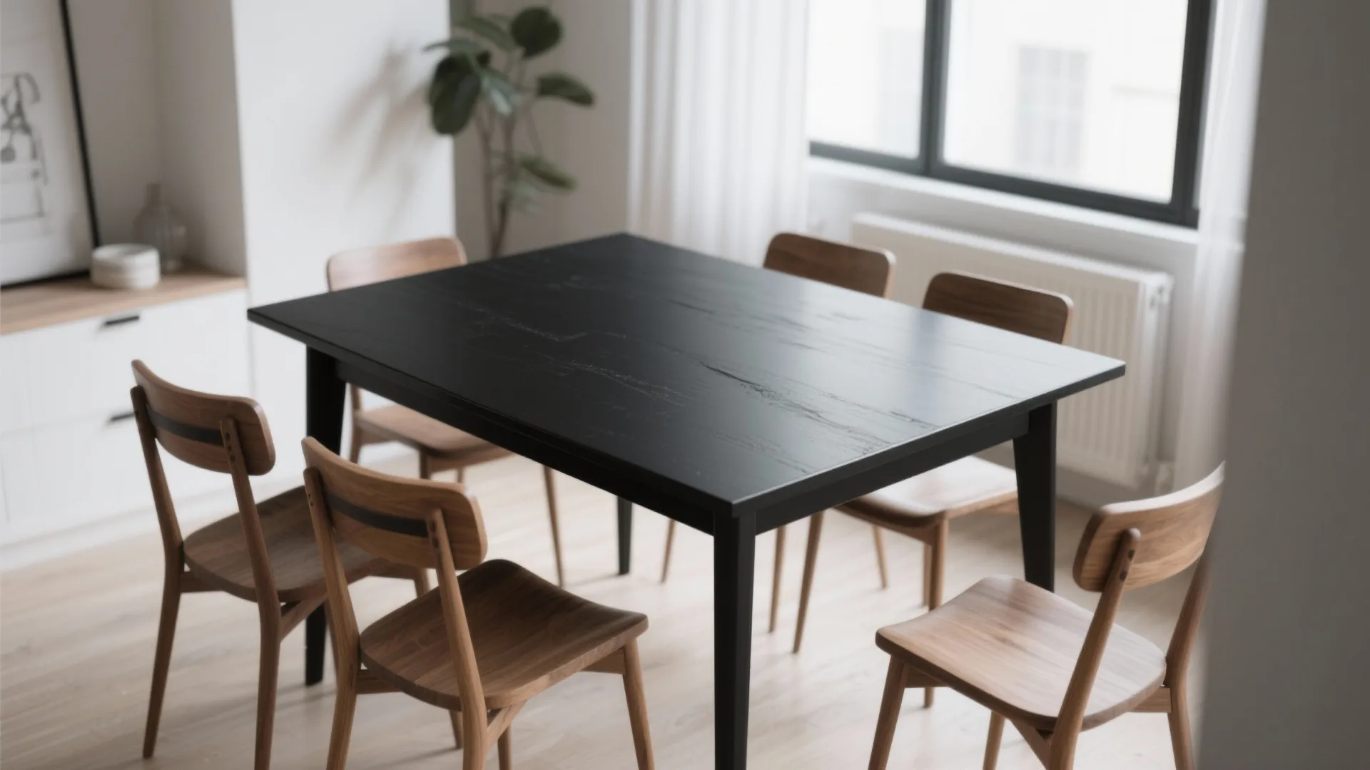Matte black dining table with rustic wooden chairs in a bright room