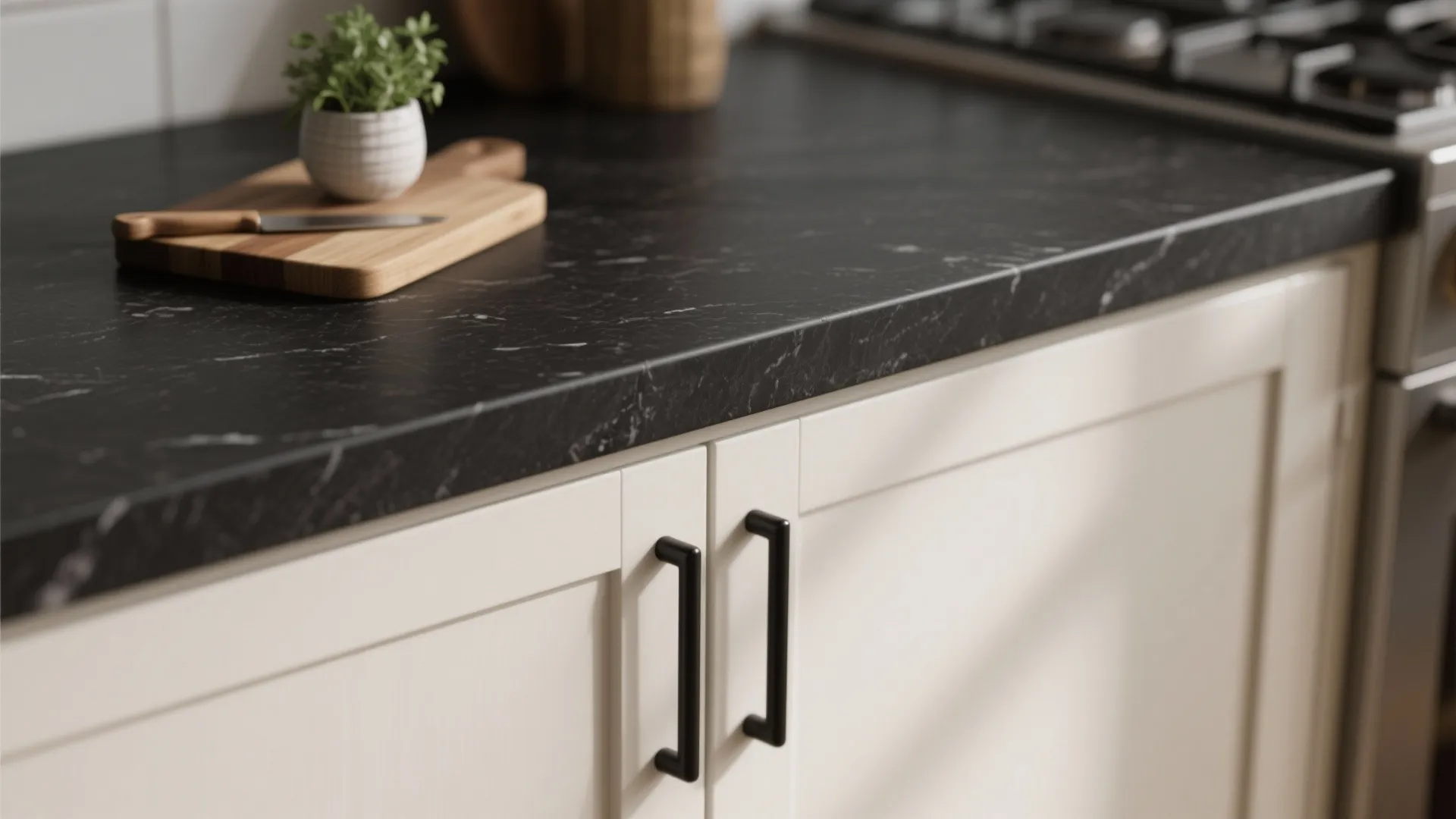 Close-up of matte black quartz countertop edge and off-white shaker cabinet with black pull