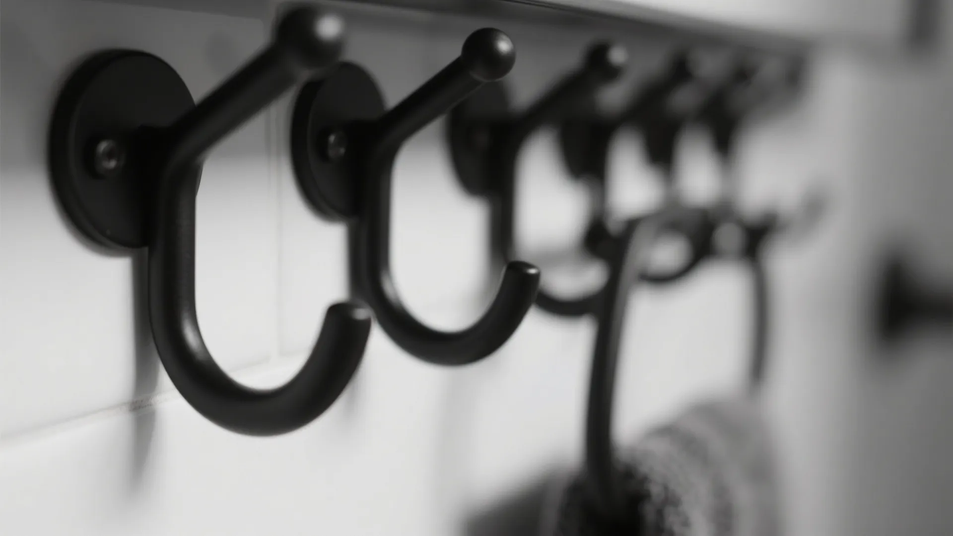 Detail view of minimal matte black towel hooks on white wall