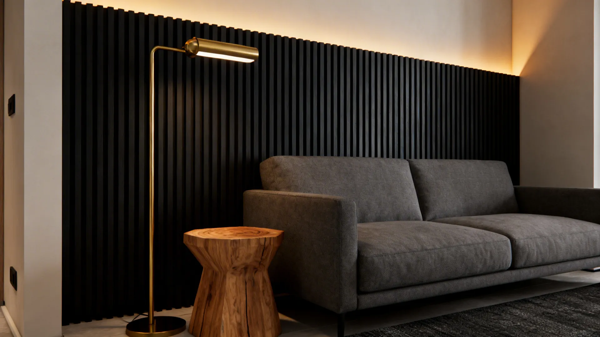 Grey sofa anchored by a matte black vertical slat accent wall with brass lighting.