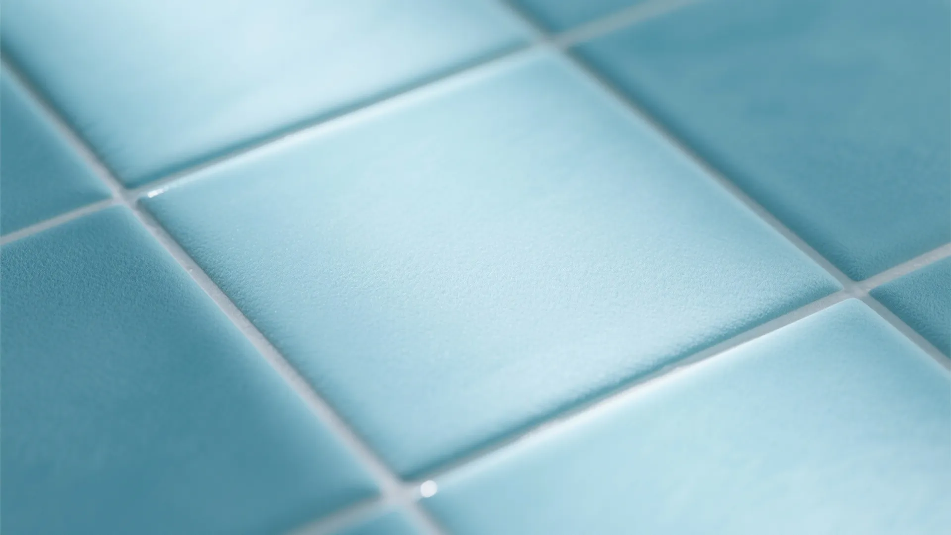 Close up of square light blue bathroom tiles with smooth matte finish and white grout