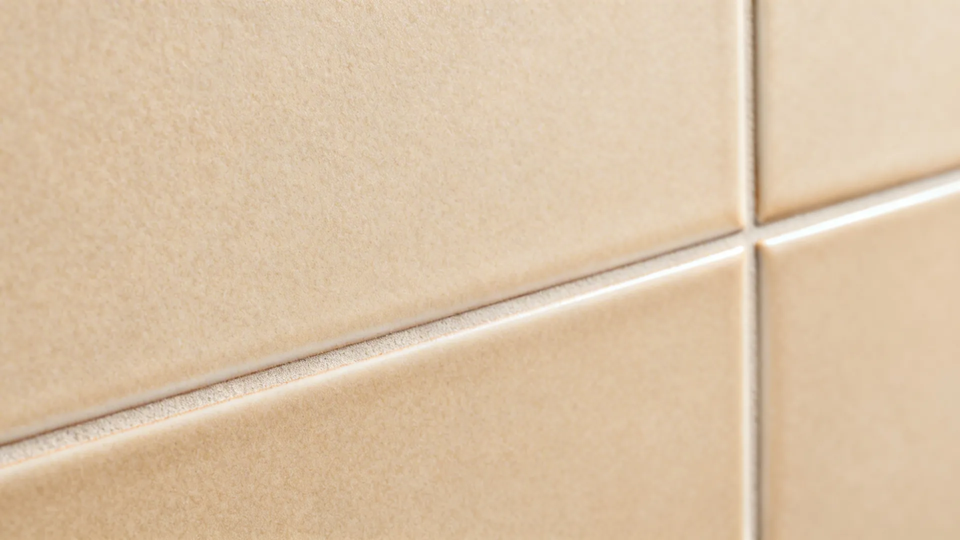 Macro view of beige matte floor tiles showing clean white grout lines and a smooth surface