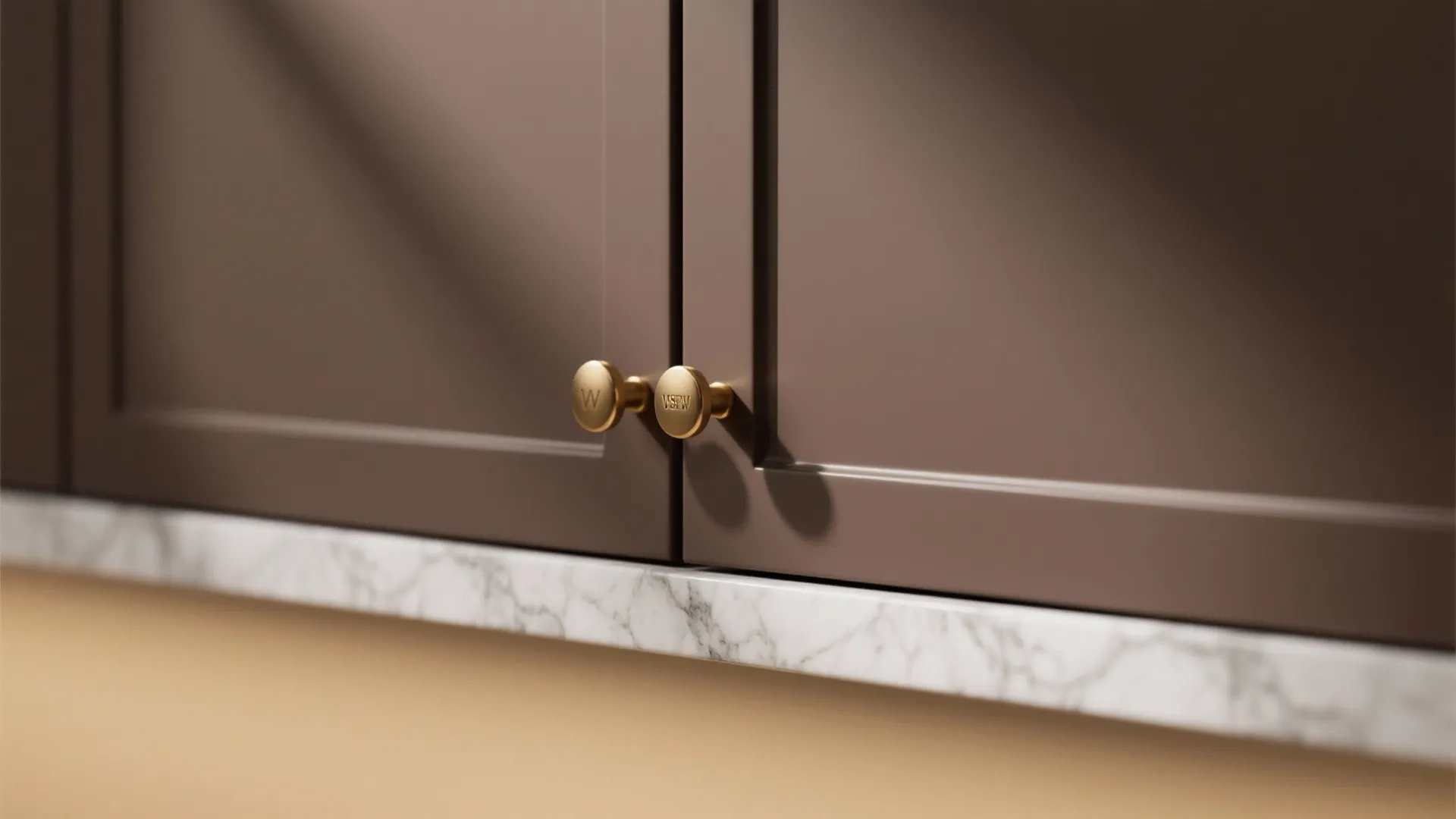 Close-up of matte chocolate brown cabinet with brass handle and marble-look quartz